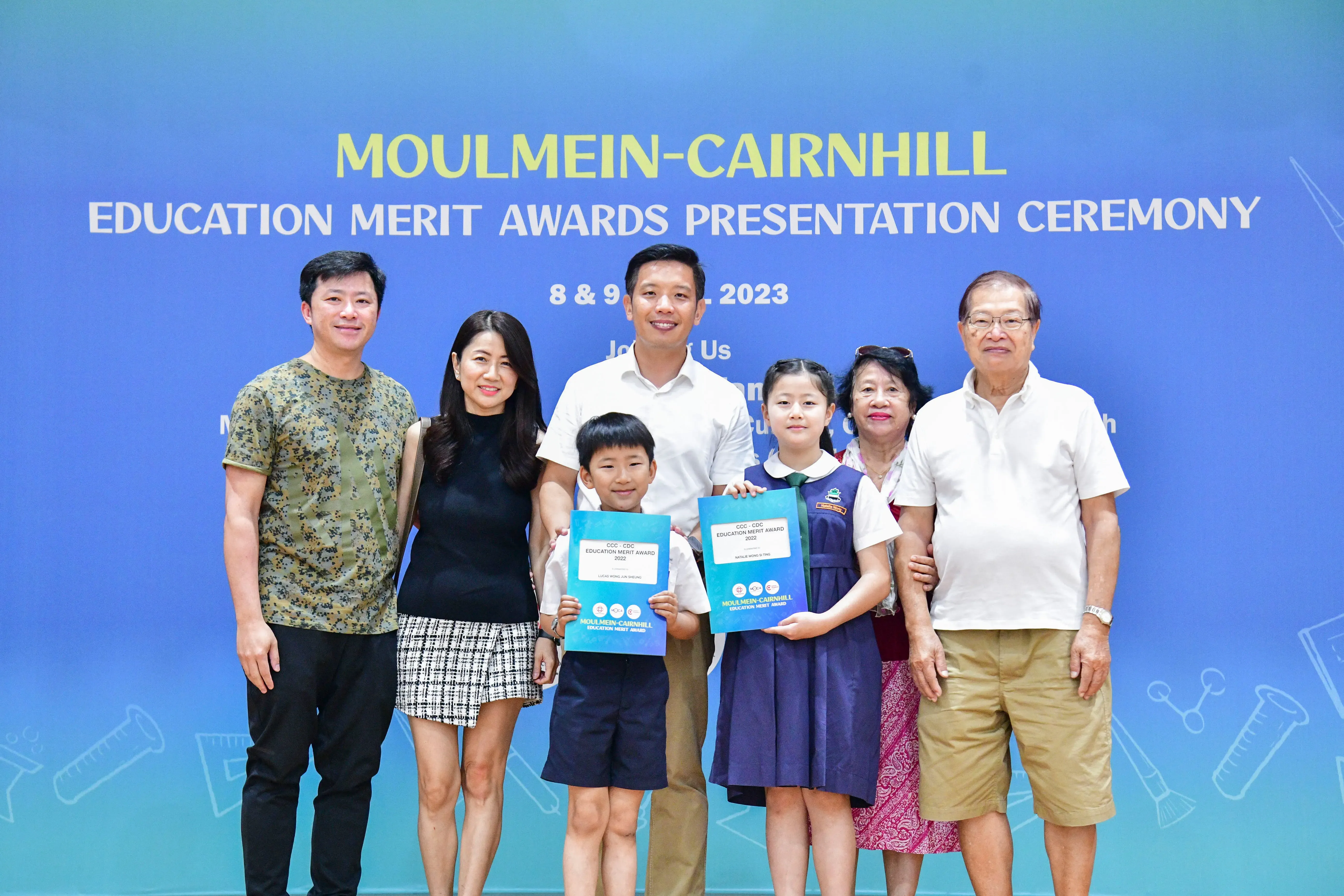 Six adults and two children pose at the Moulmein-Cairnhill Education Merit Awards Presentation Ceremony 2023.