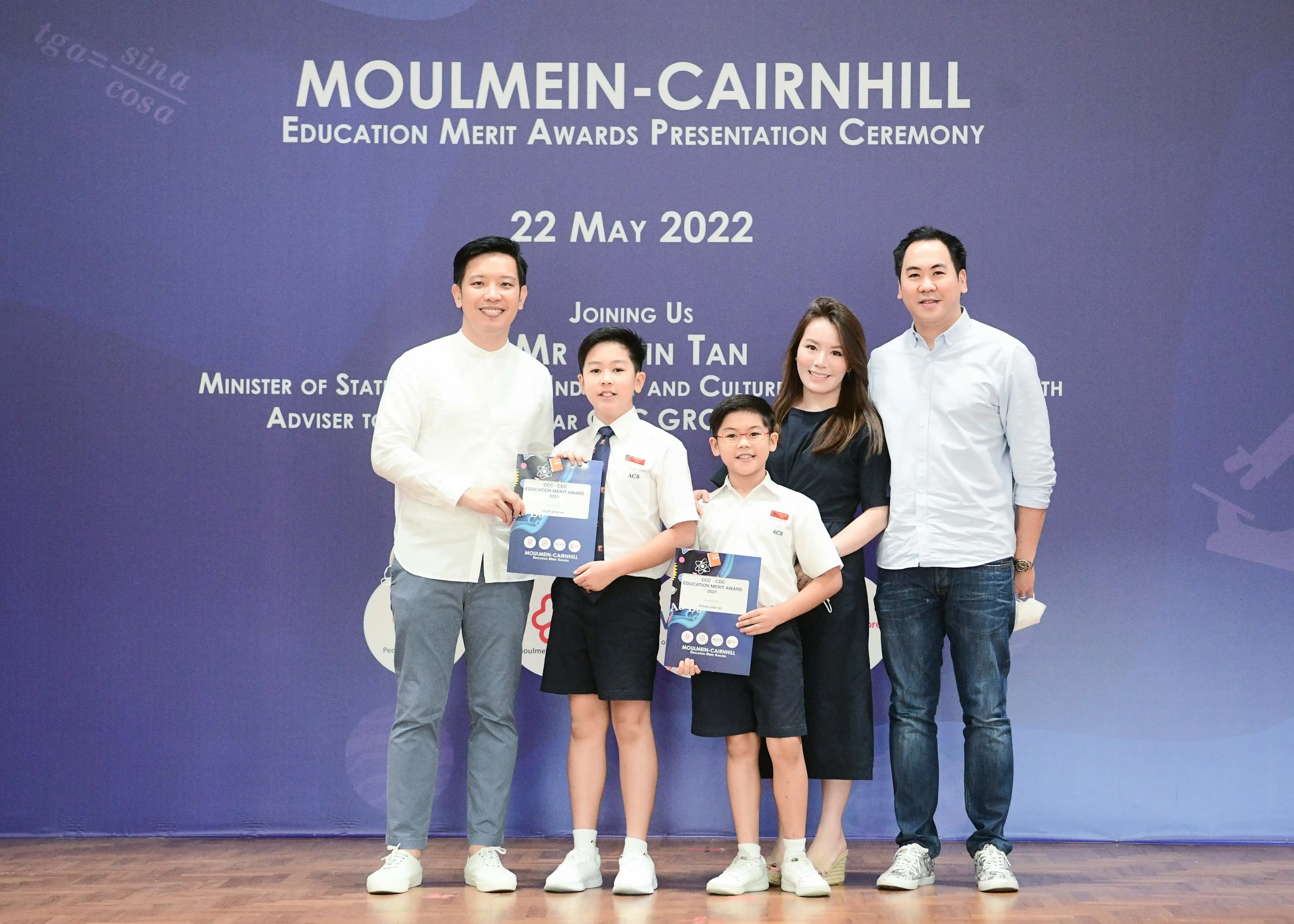 Two adults and two young boys in school uniforms pose with award certificates at Moulmein-Cairnhill Education Merit Awards 2022.