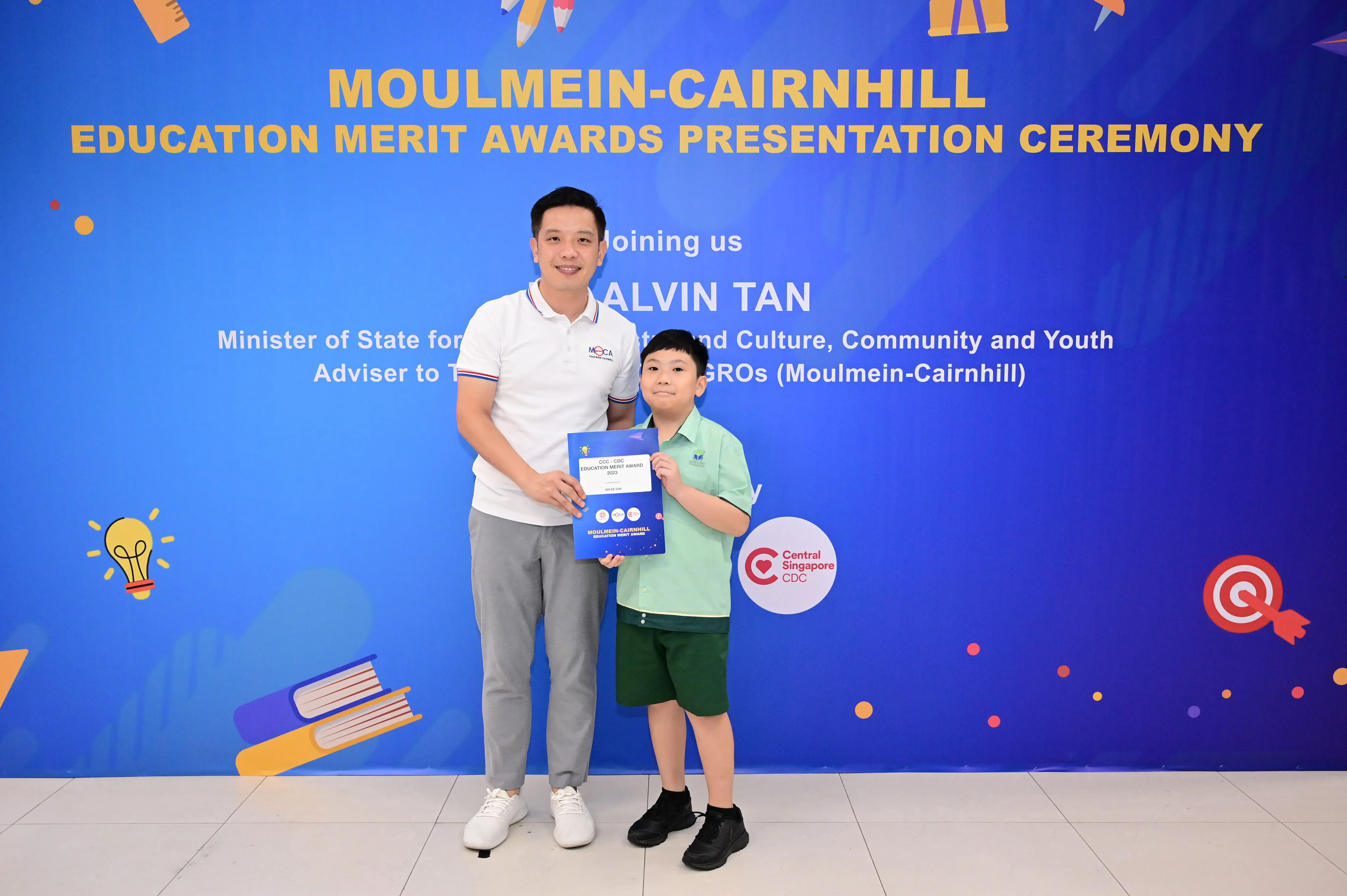 Man and young boy holding an award certificate at Moulmein-Cairnhill Education Merit Awards Presentation Ceremony.