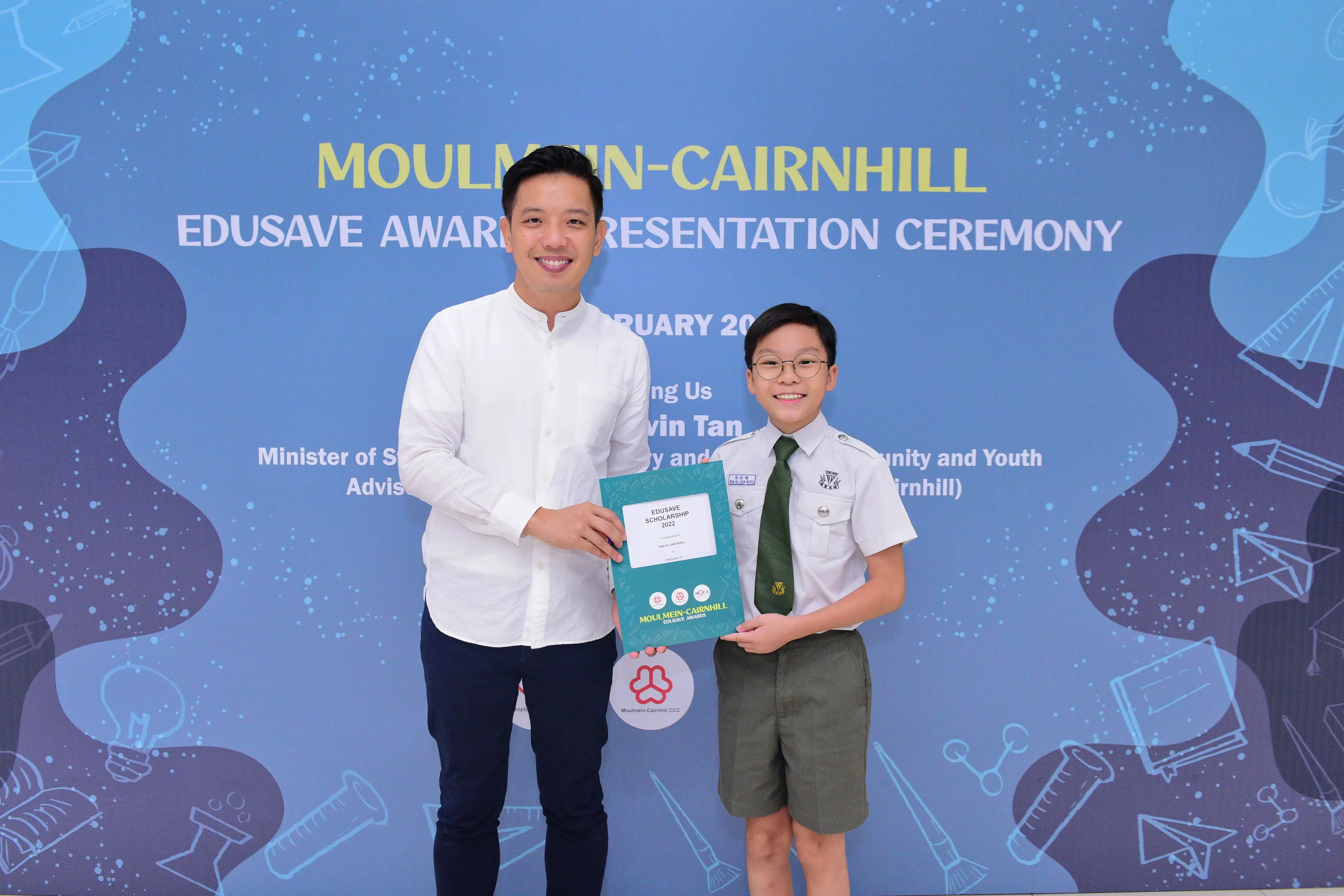 An adult and a uniformed student hold a certificate at the Moulmein-Cairnhill Edusave Award Presentation Ceremony.