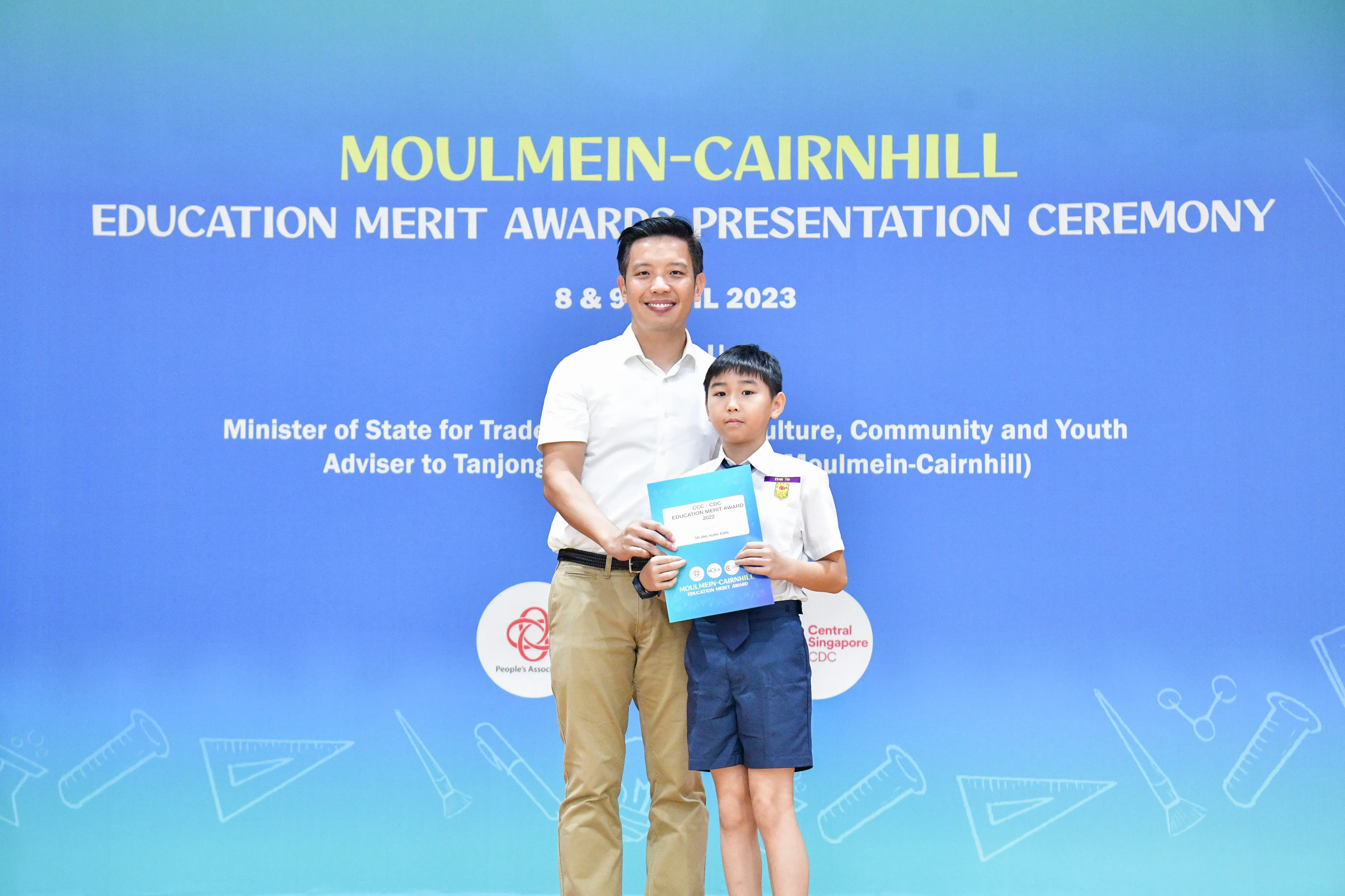A man and a young boy pose holding an award at the Moulmein-Cairnhill Education Merit Awards Ceremony 2023.