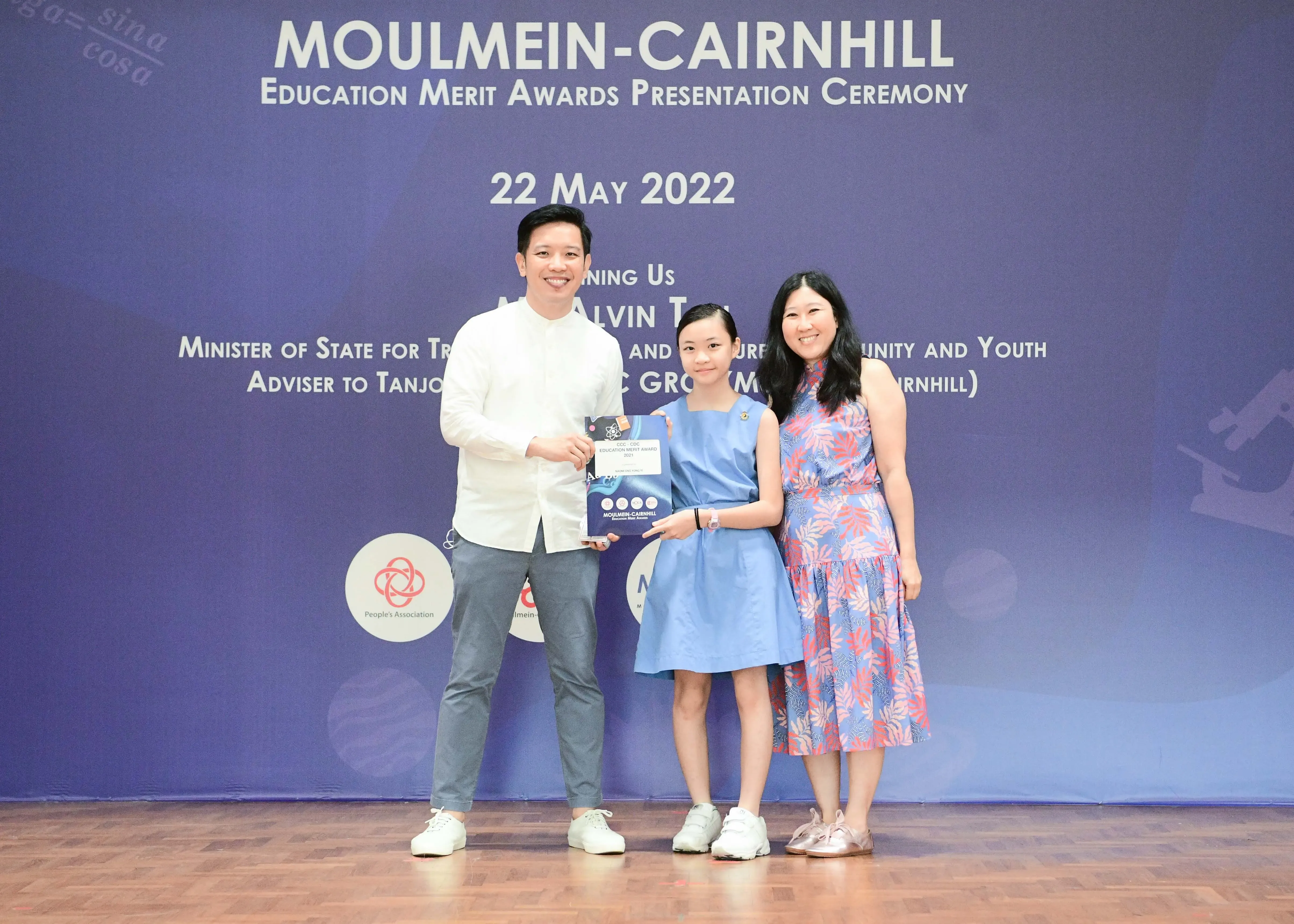 Three people pose at the Moulmein-Cairnhill Education Merit Awards Ceremony on 22 May 2022, holding an award.