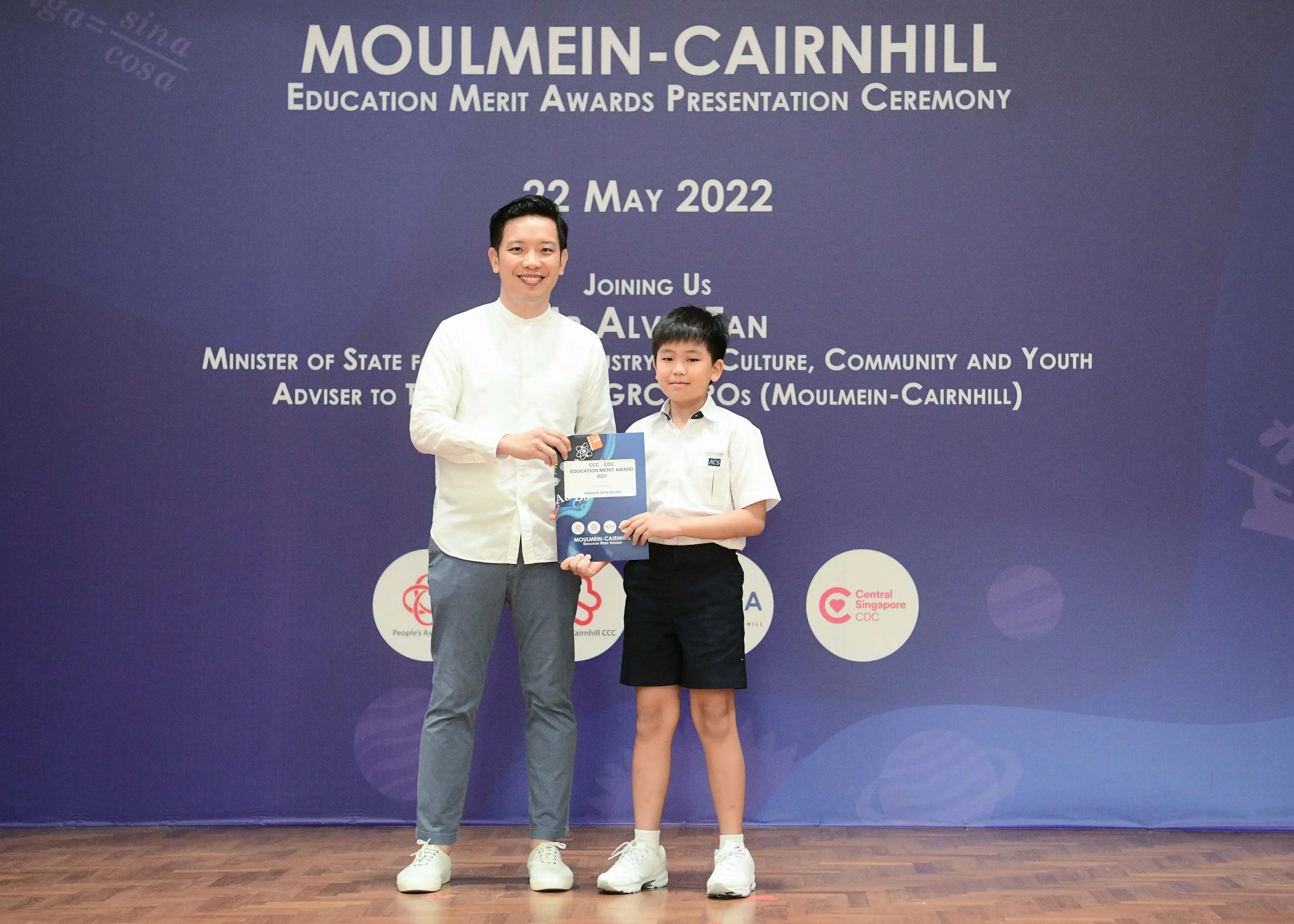 A man and a young boy hold an award certificate at the Moulmein-Cairnhill Education Merit Awards on 22 May 2022.