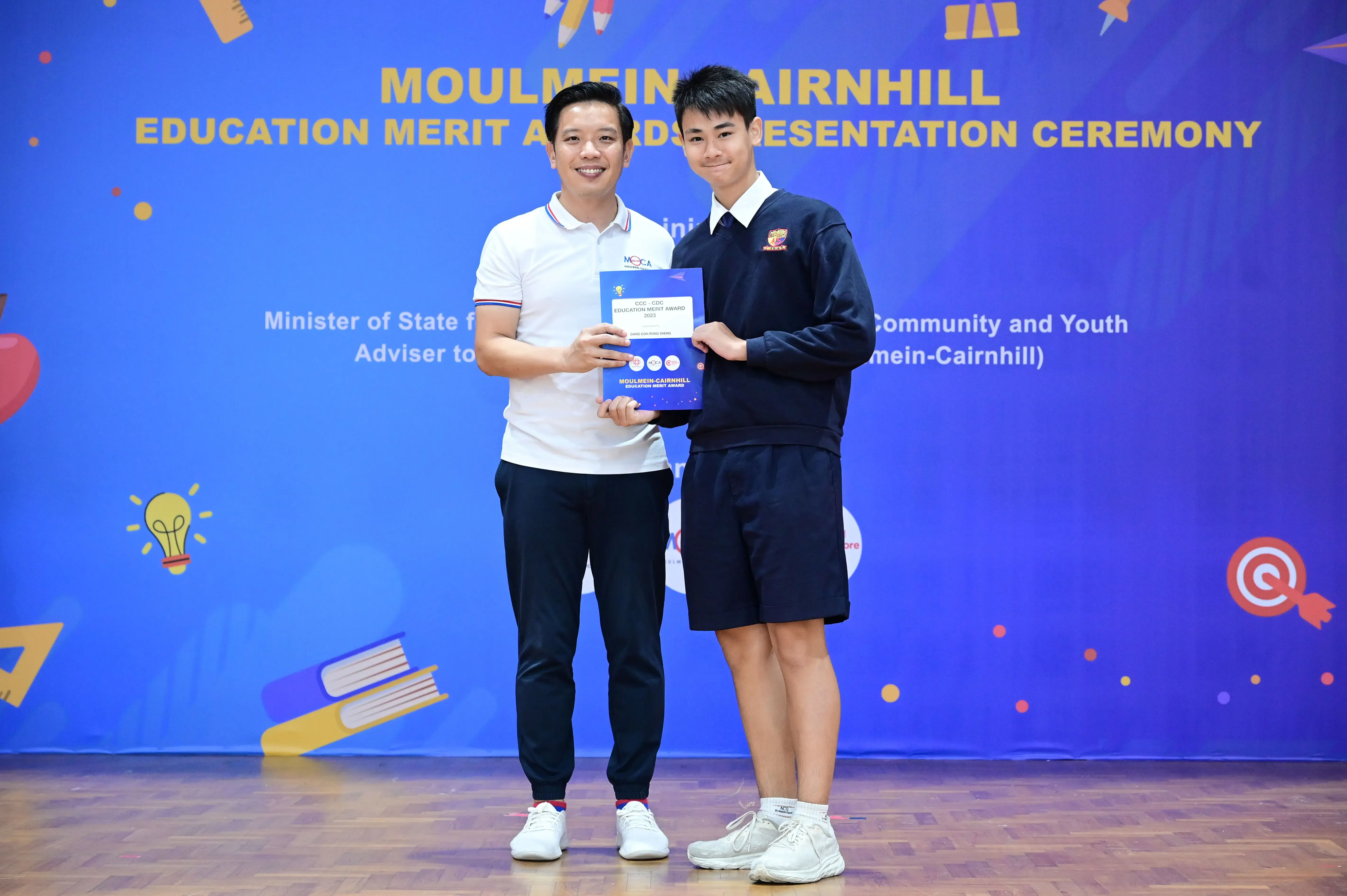 Two men hold an award certificate at the Moulmein-Cairnhill Education Merit Awards Presentation Ceremony.