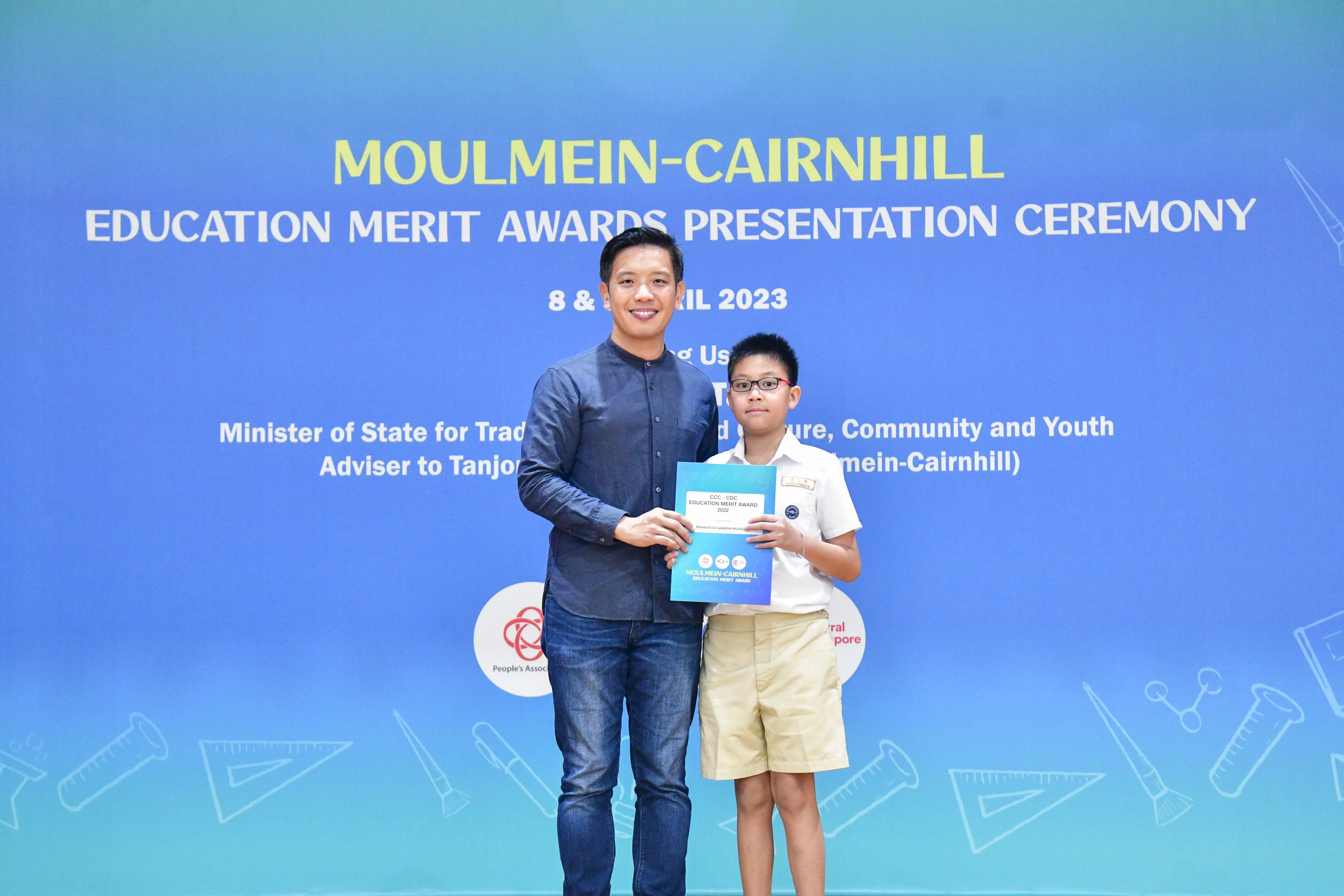 Adult man and young boy holding a certificate together at Moulmein-Cairnhill Education Merit Awards Ceremony 2023.