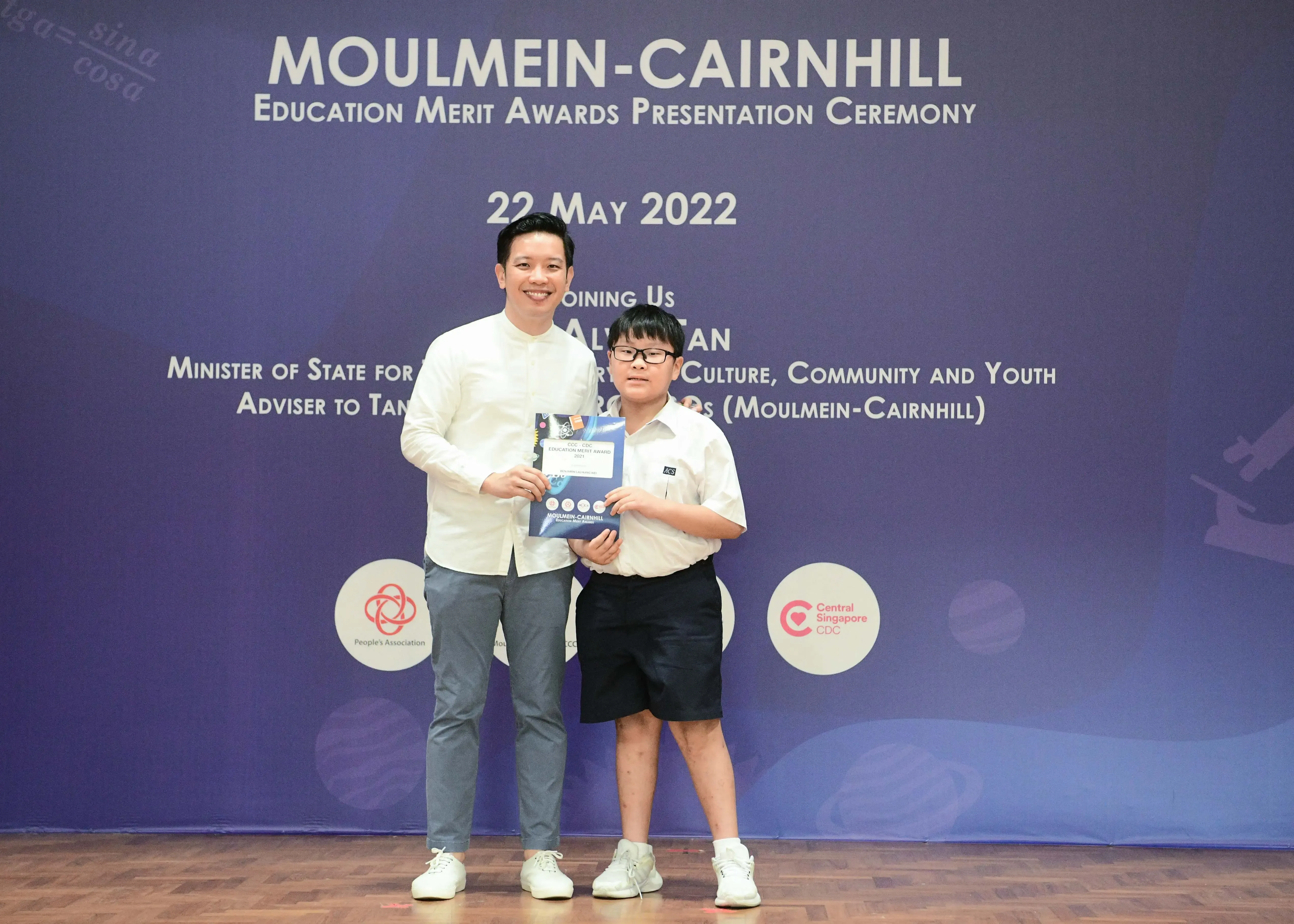 A man and a young boy hold an award booklet at the Moulmein-Cairnhill Education Merit Awards on 22 May 2022.
