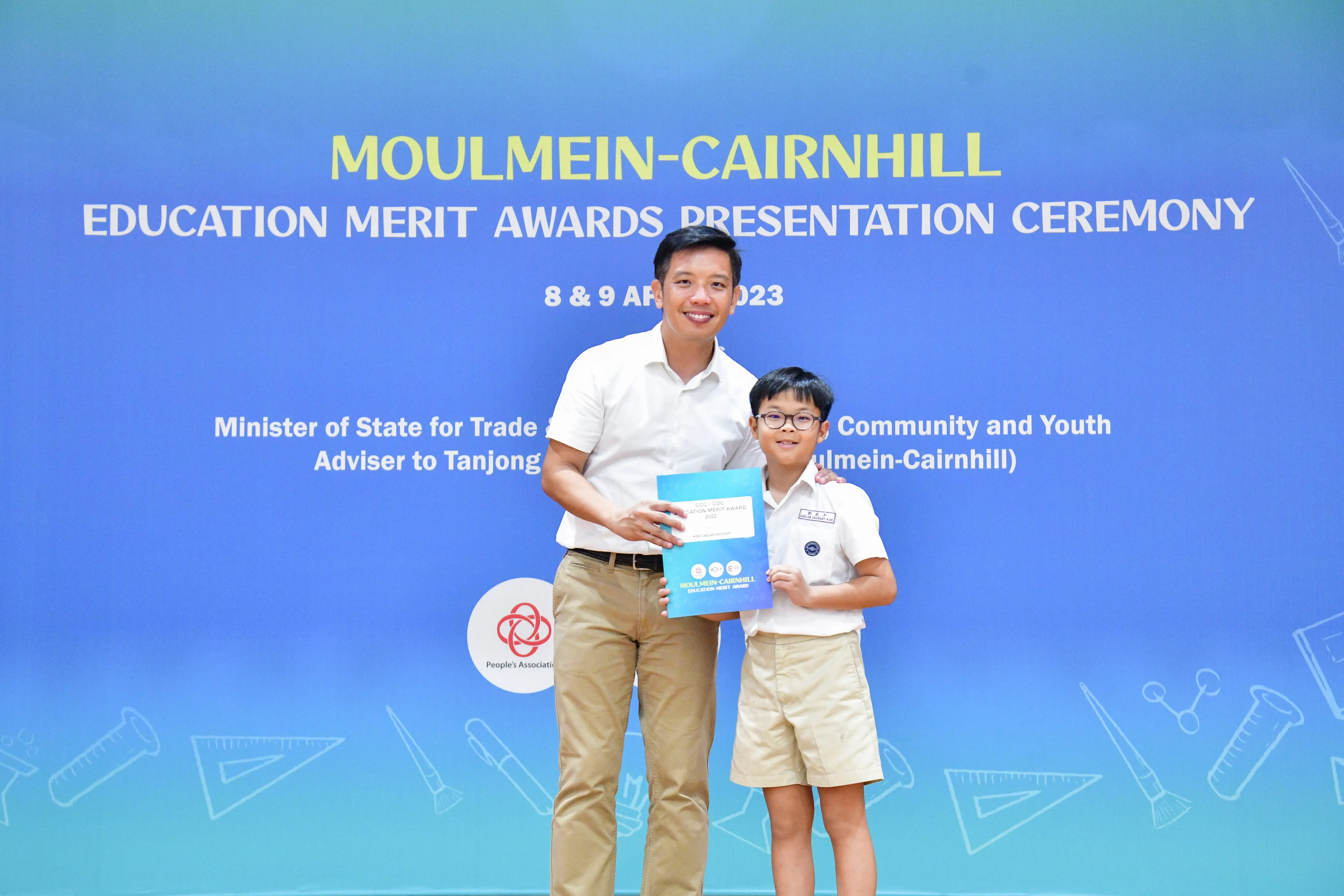 A man and a young boy in school uniform pose with an award at the Moulmein-Cairnhill Education Merit Awards 2023.