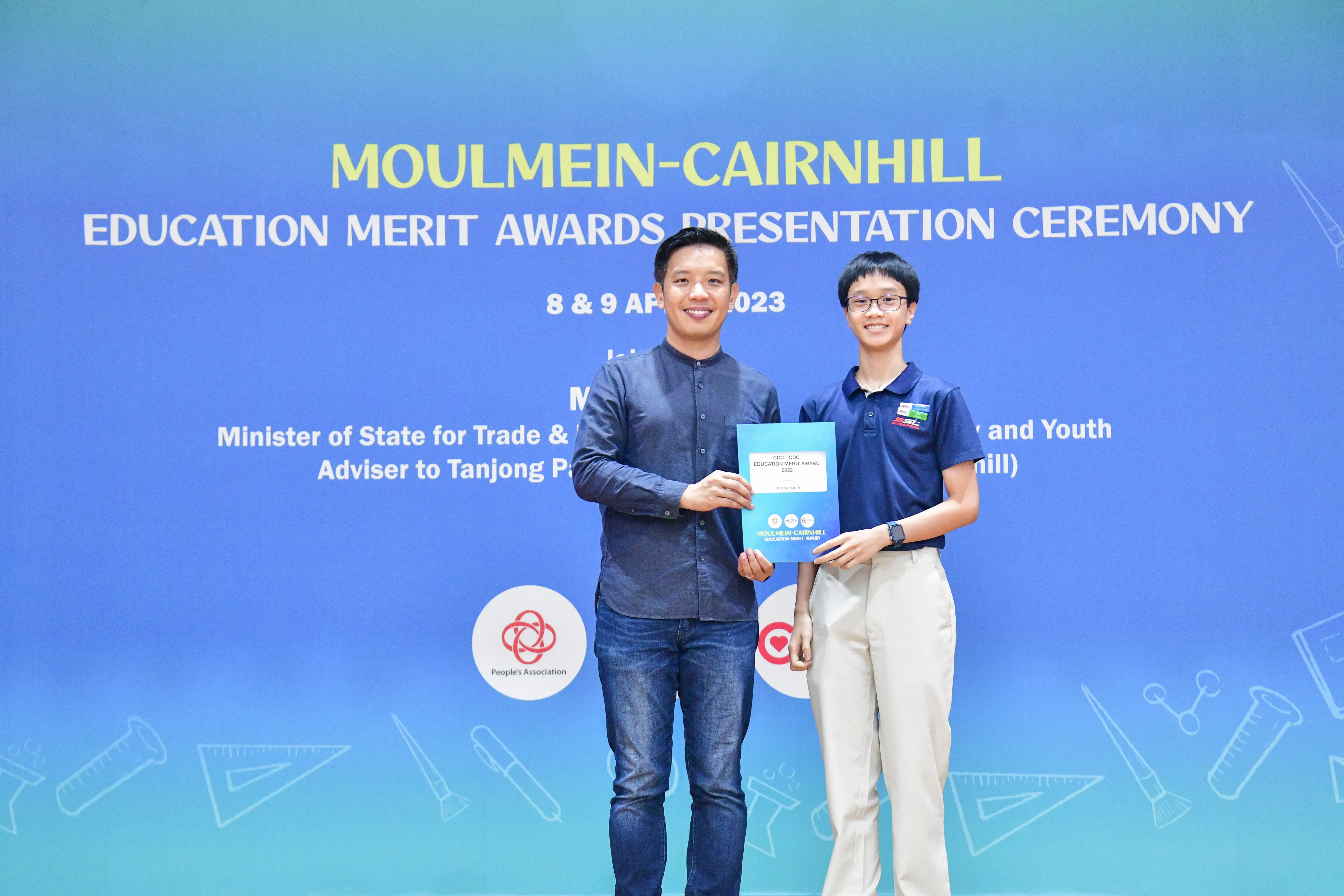 Two people smile while holding an award certificate at the Moulmein-Cairnhill Education Merit Awards Ceremony, April 2023.