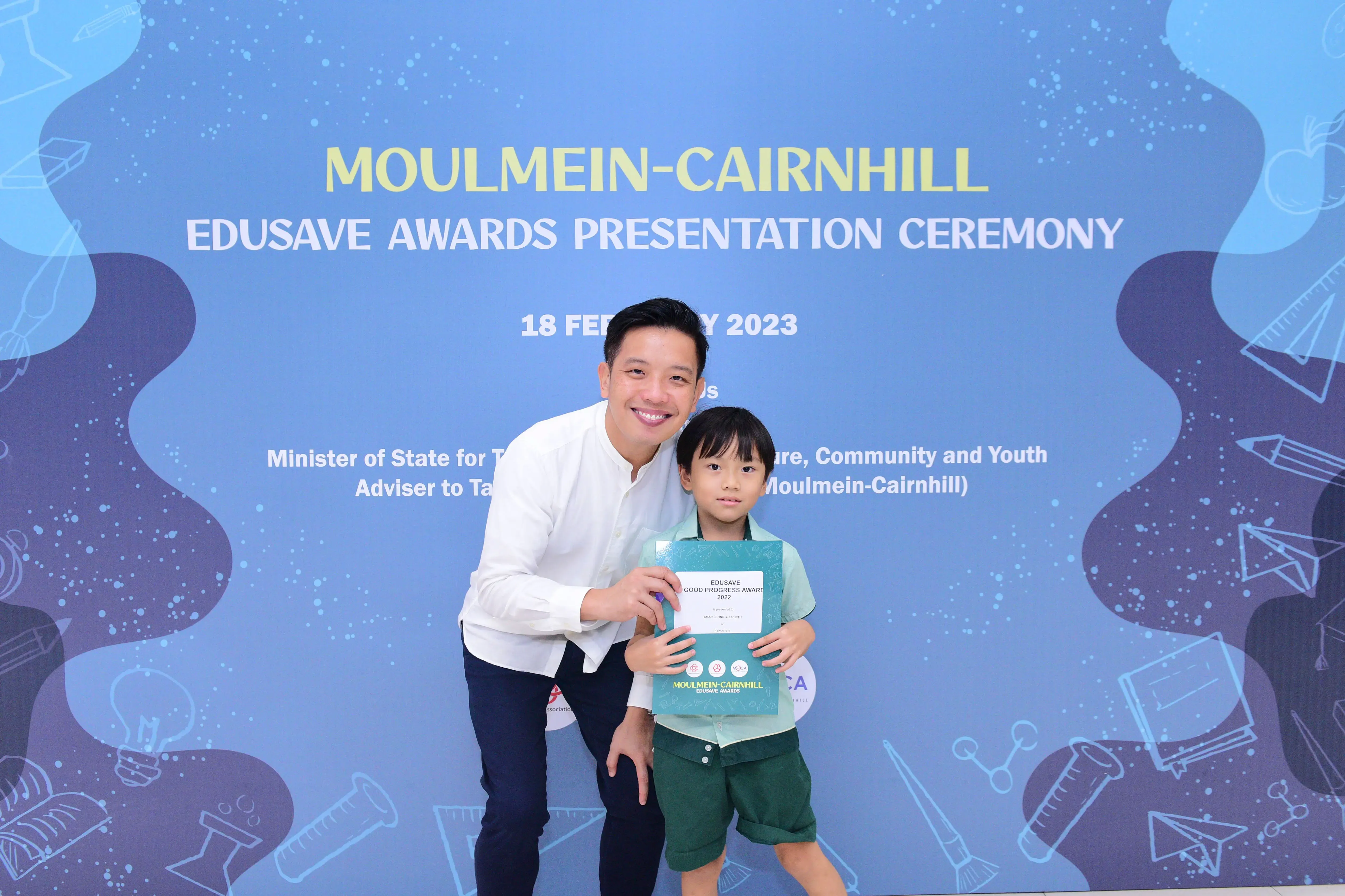 A man and a young boy pose with an Edusave award certificate at the Moulmein-Cairnhill Awards Ceremony on 18 February 2023.