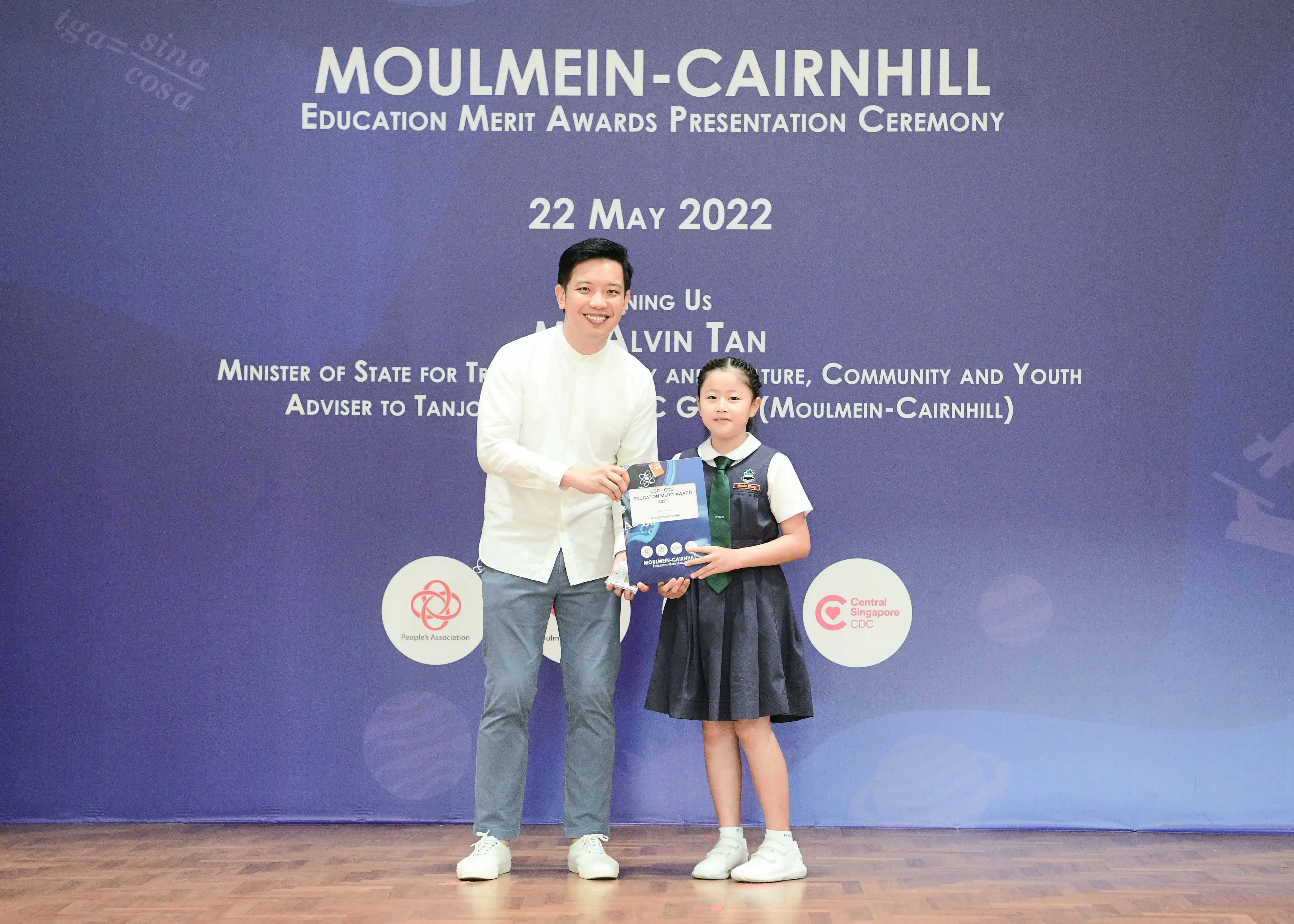A man and a young girl in school uniform pose together holding an award at the Moulmein-Cairnhill Education Merit Awards 2022.