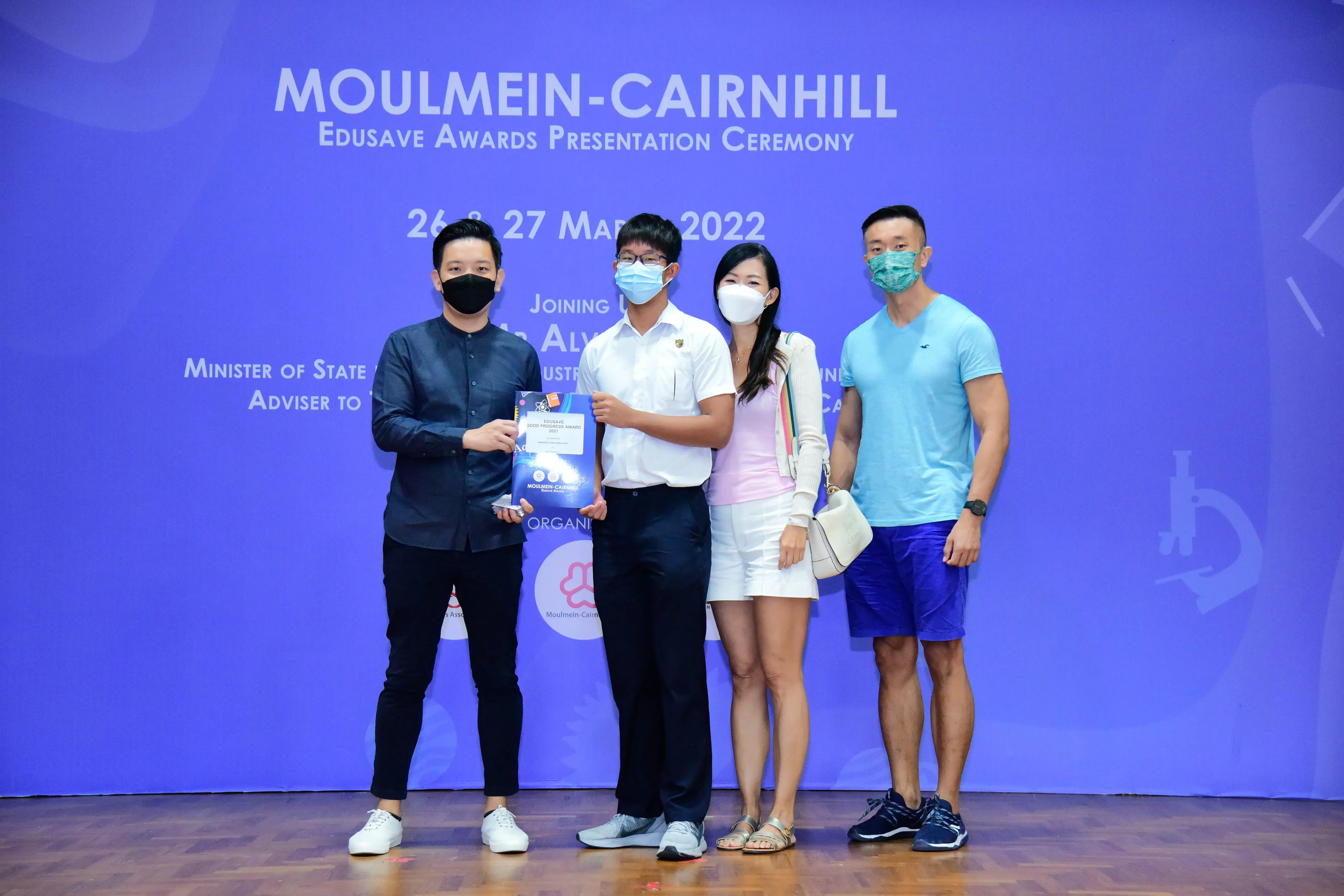 Four masked people pose at the Moulmein-Cairnhill Edusave Awards Presentation Ceremony on 26-27 March 2022.