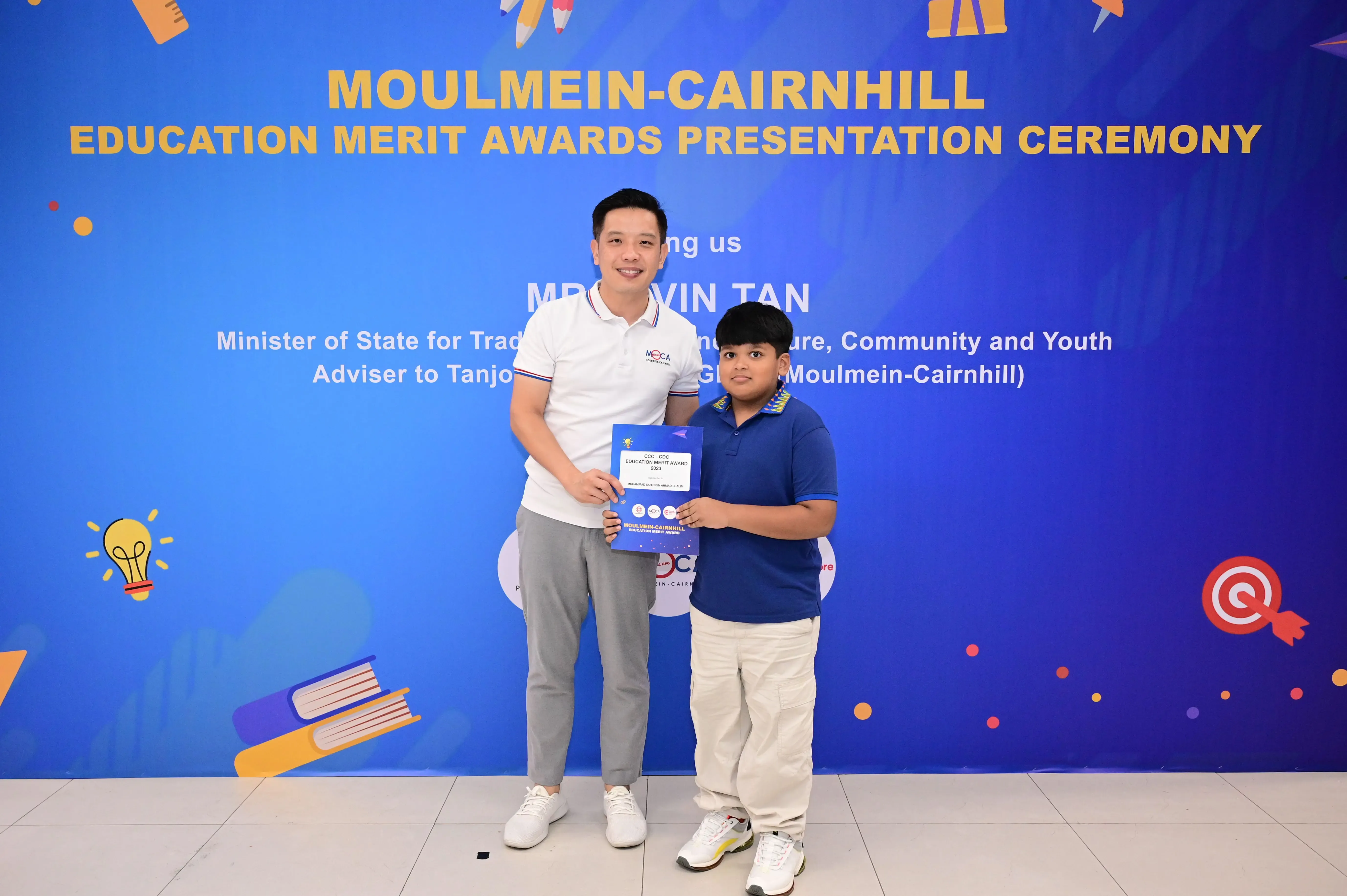Man and young boy holding a certificate at Moulmein-Cairnhill Education Merit Awards Presentation Ceremony.