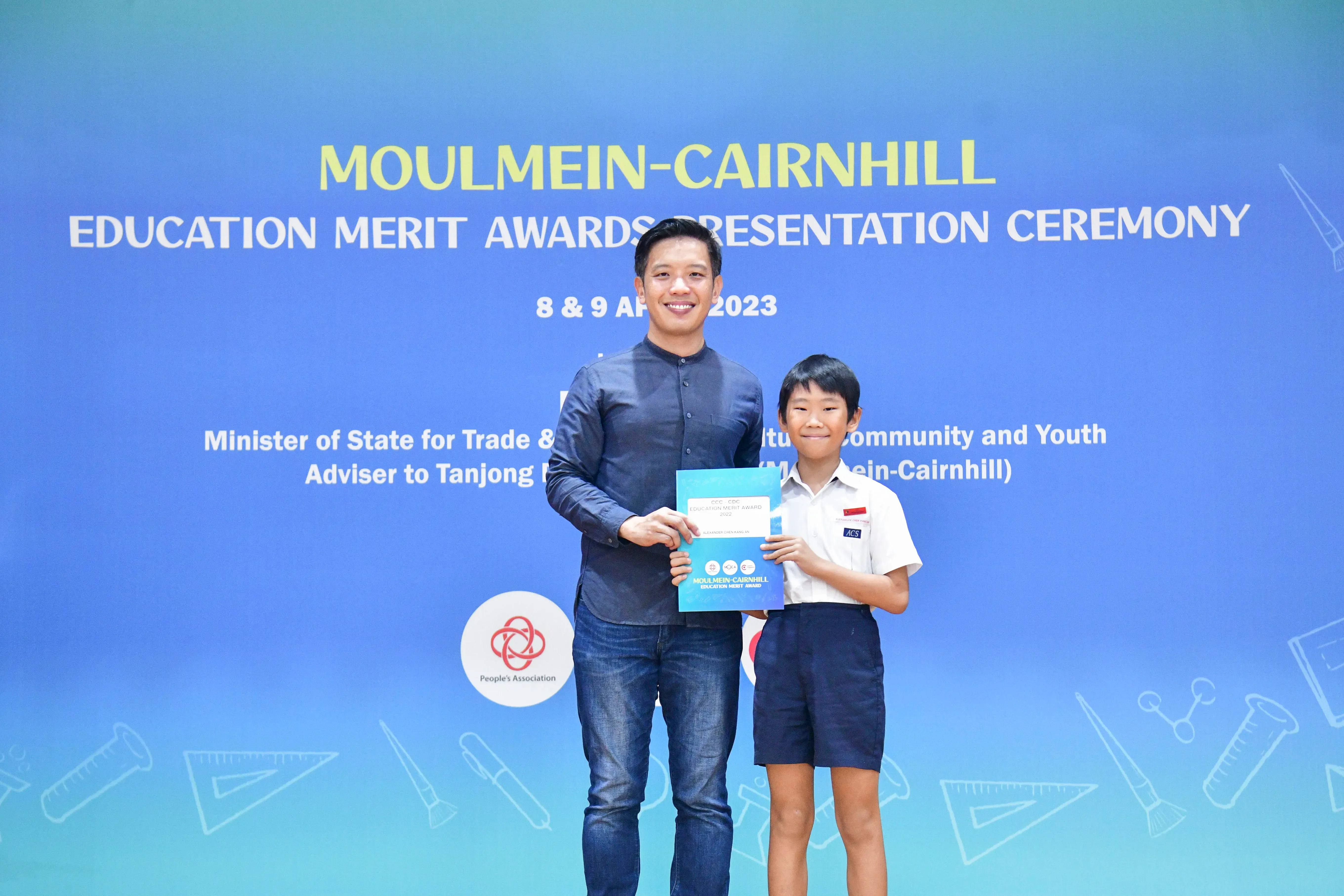 An adult and a young student hold an award certificate at the Moulmein-Cairnhill Education Merit Awards 2023.
