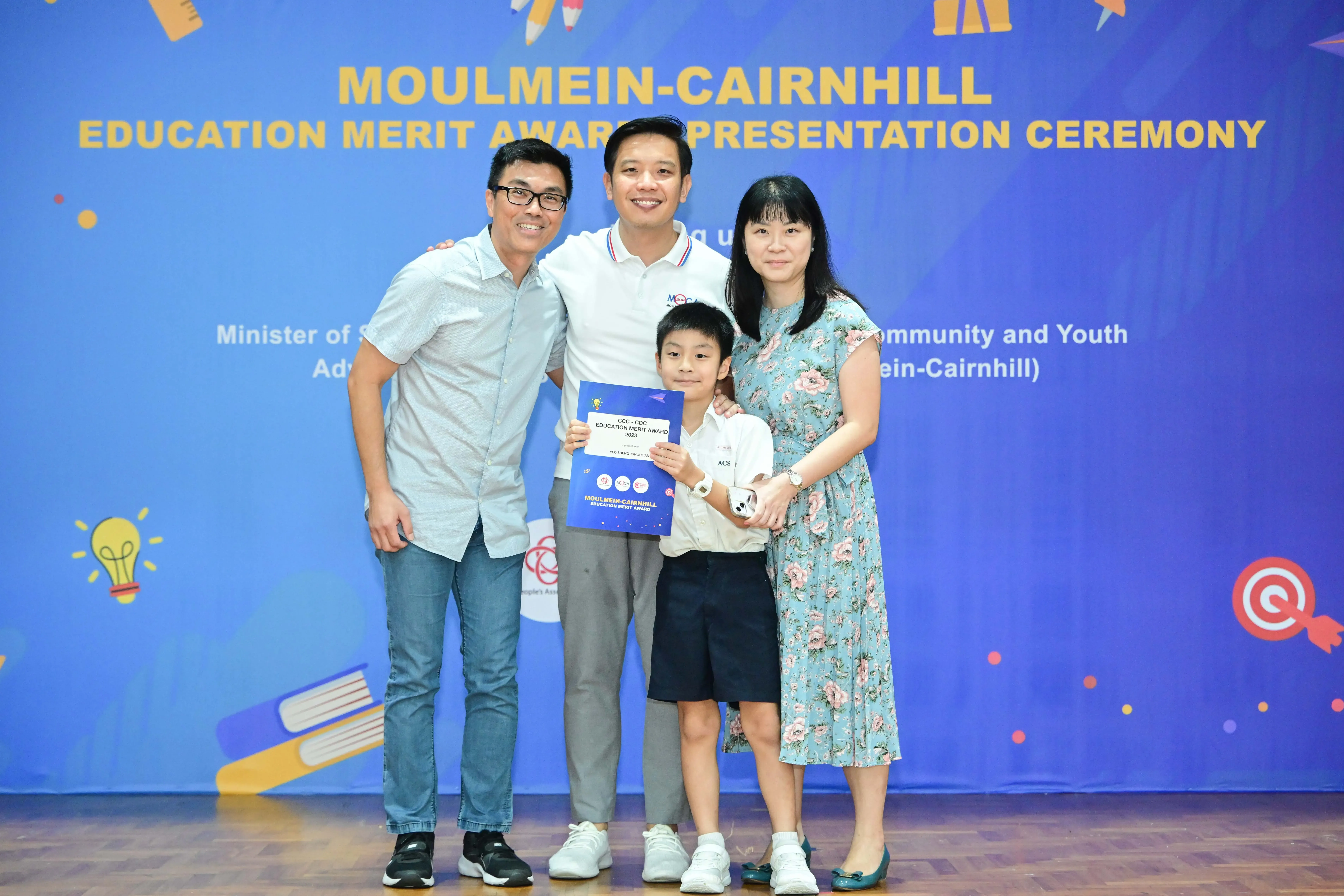 Three adults and a boy holding an award certificate pose at the Moulmein-Cairnhill Education Merit Award Ceremony.
