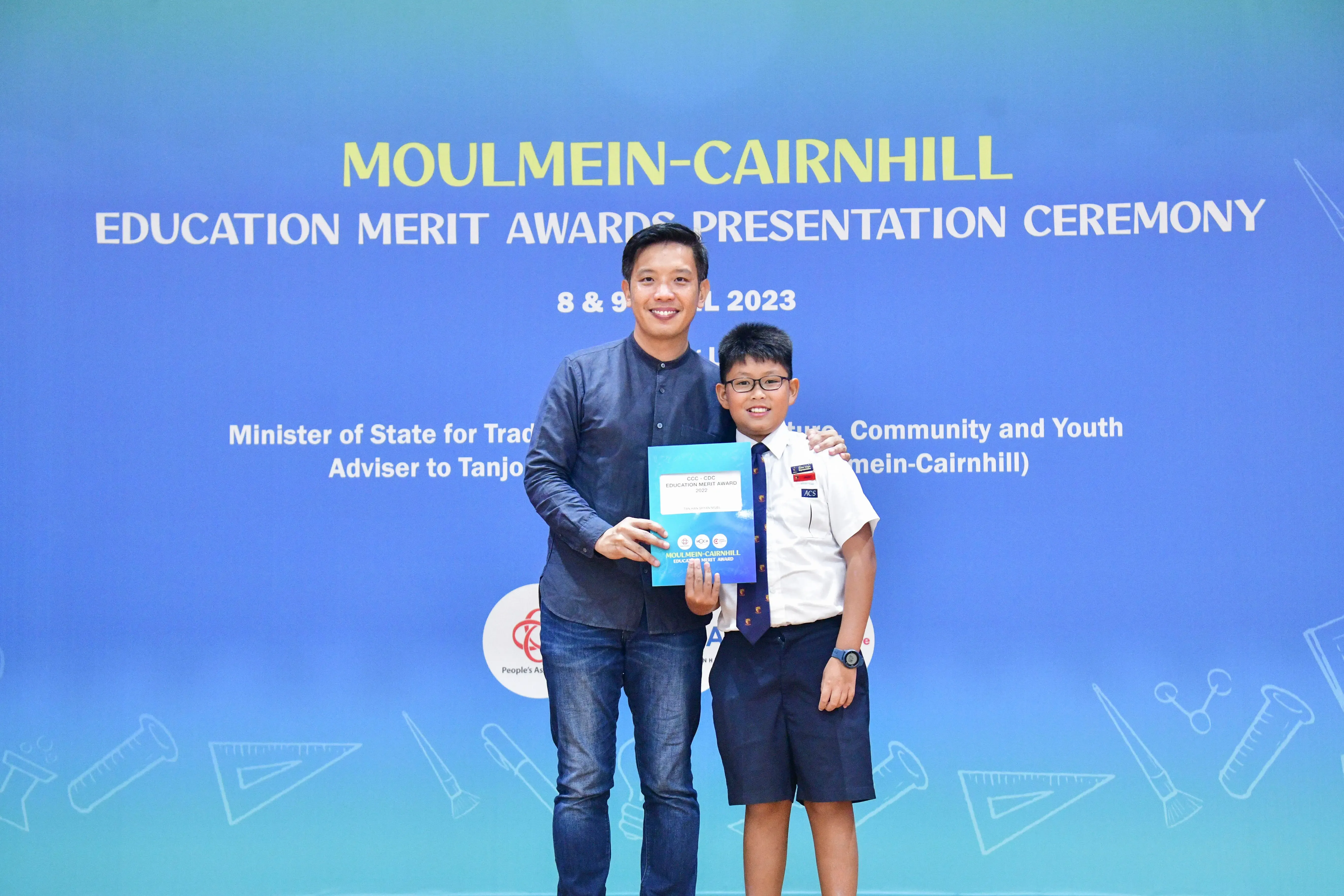 Man and young boy in school uniform pose holding an award at Moulmein-Cairnhill Education Merit Awards 2023.