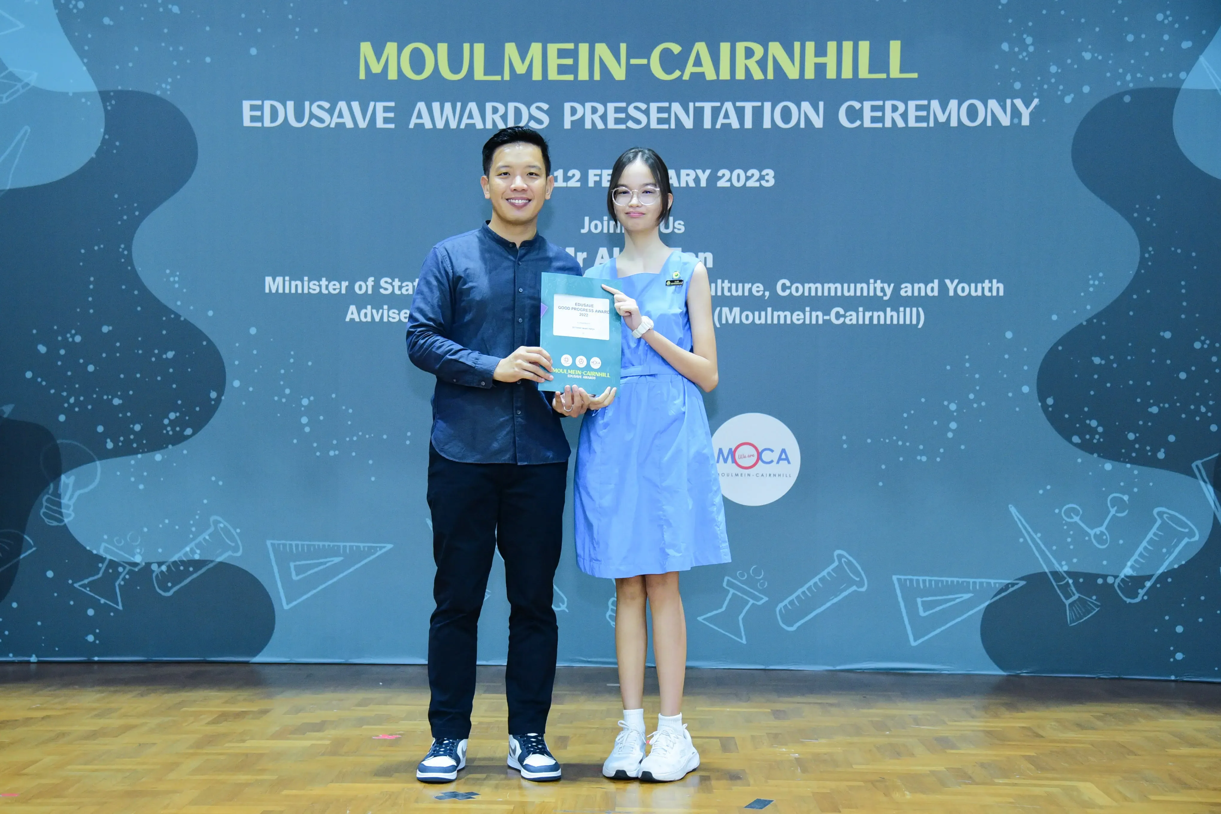 A man and a young girl hold a certificate at the Moulmein-Cairnhill Edusave Awards Presentation Ceremony 2023.