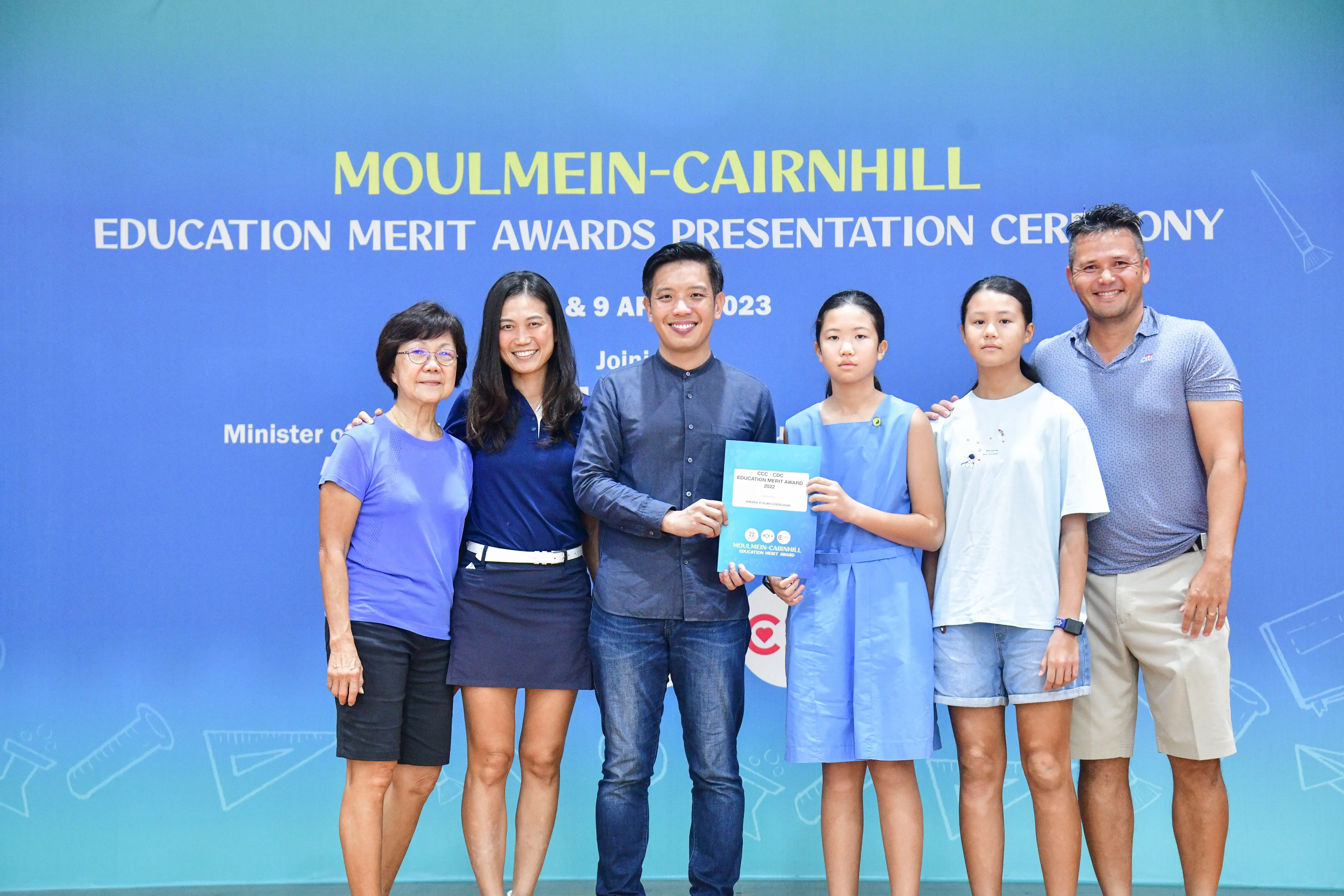 Six people pose together holding an award booklet at the Moulmein-Cairnhill Education Merit Awards Ceremony, April 2023.