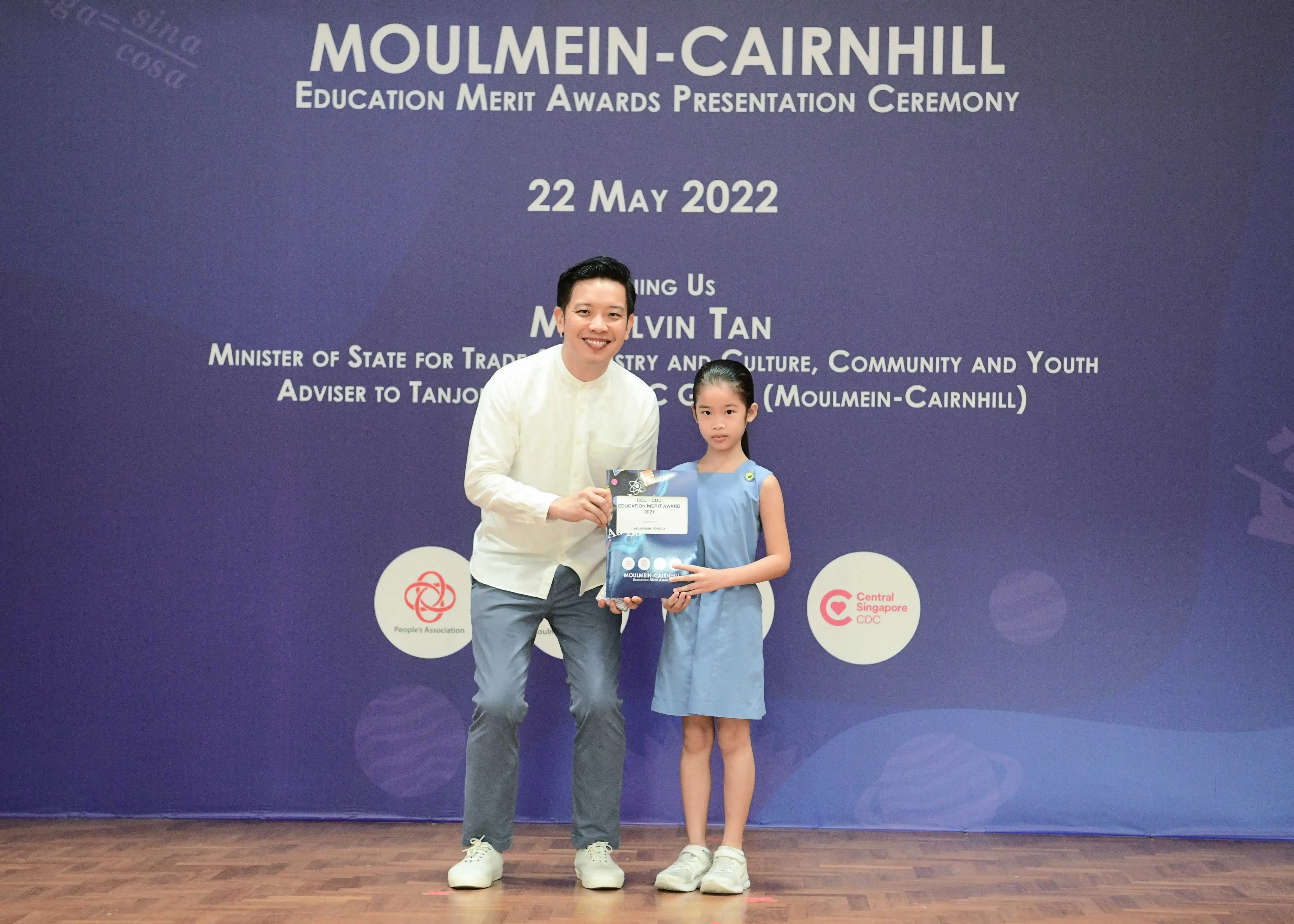 A man and a young girl hold an award together at the Moulmein-Cairnhill Education Merit Awards ceremony on 22 May 2022.