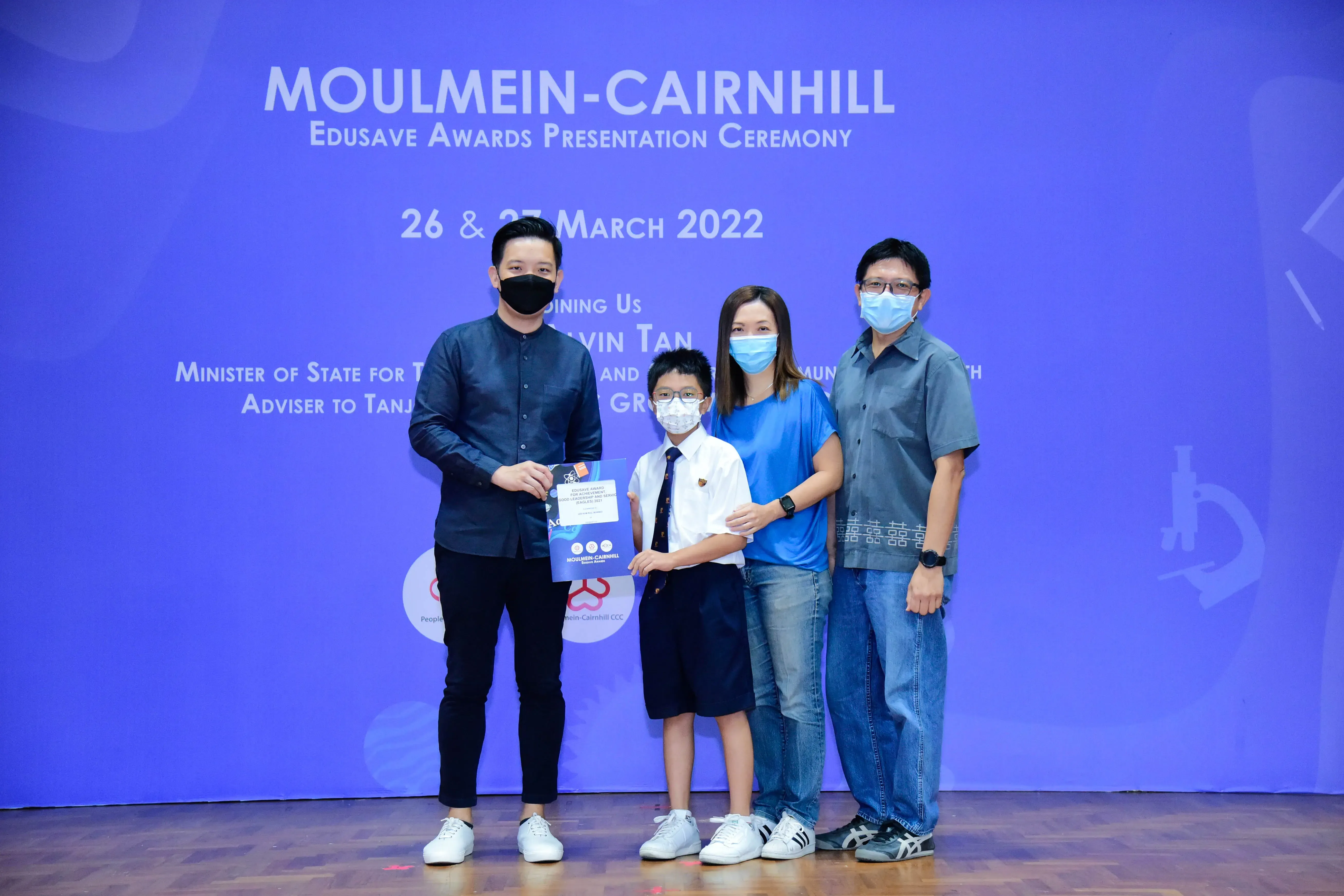 Four masked people pose at the Moulmein-Cairnhill Edusave Awards Presentation Ceremony on 26-27 March 2022.