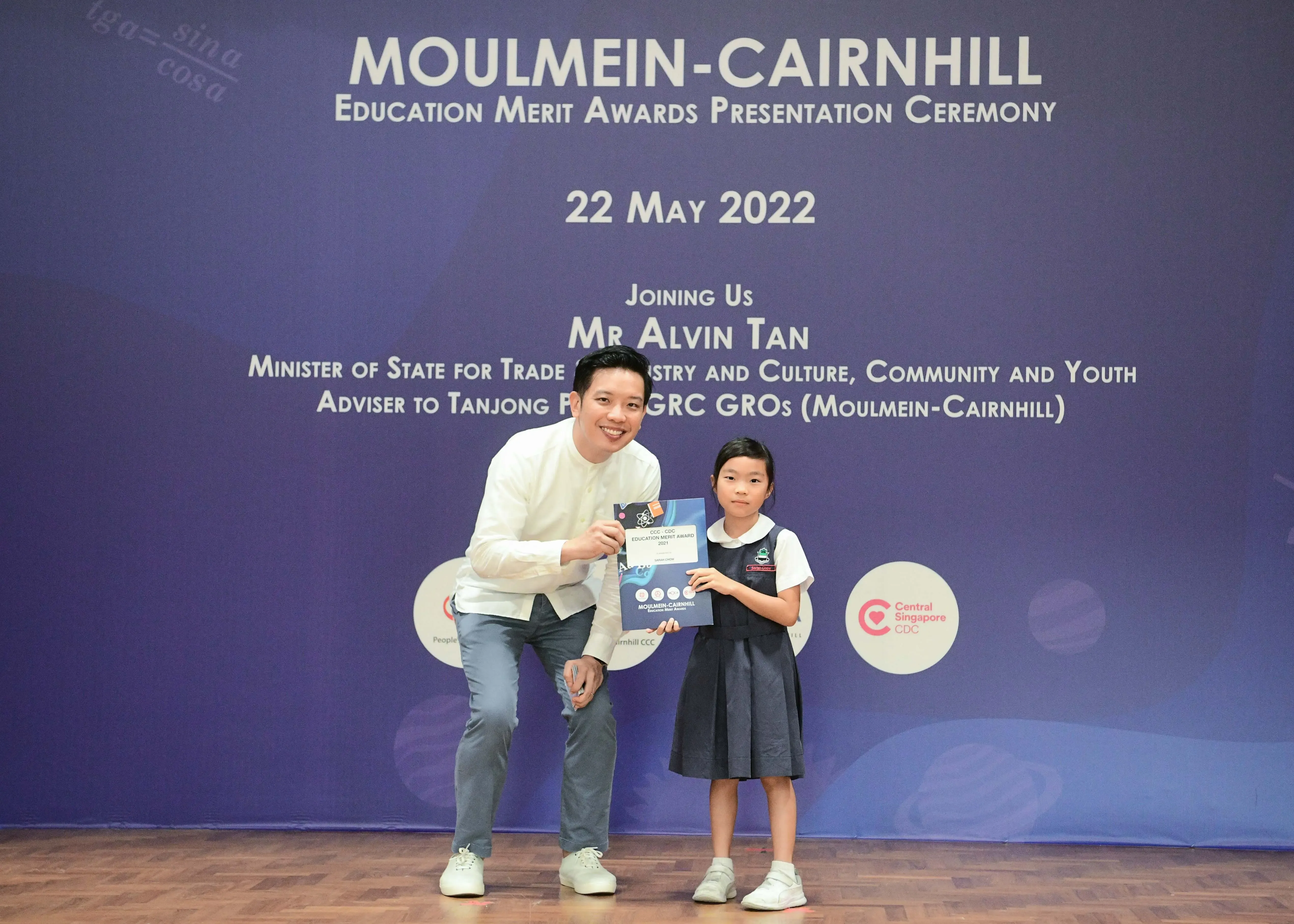A man and a young girl hold a certificate at the Moulmein-Cairnhill Education Merit Awards on 22 May 2022.