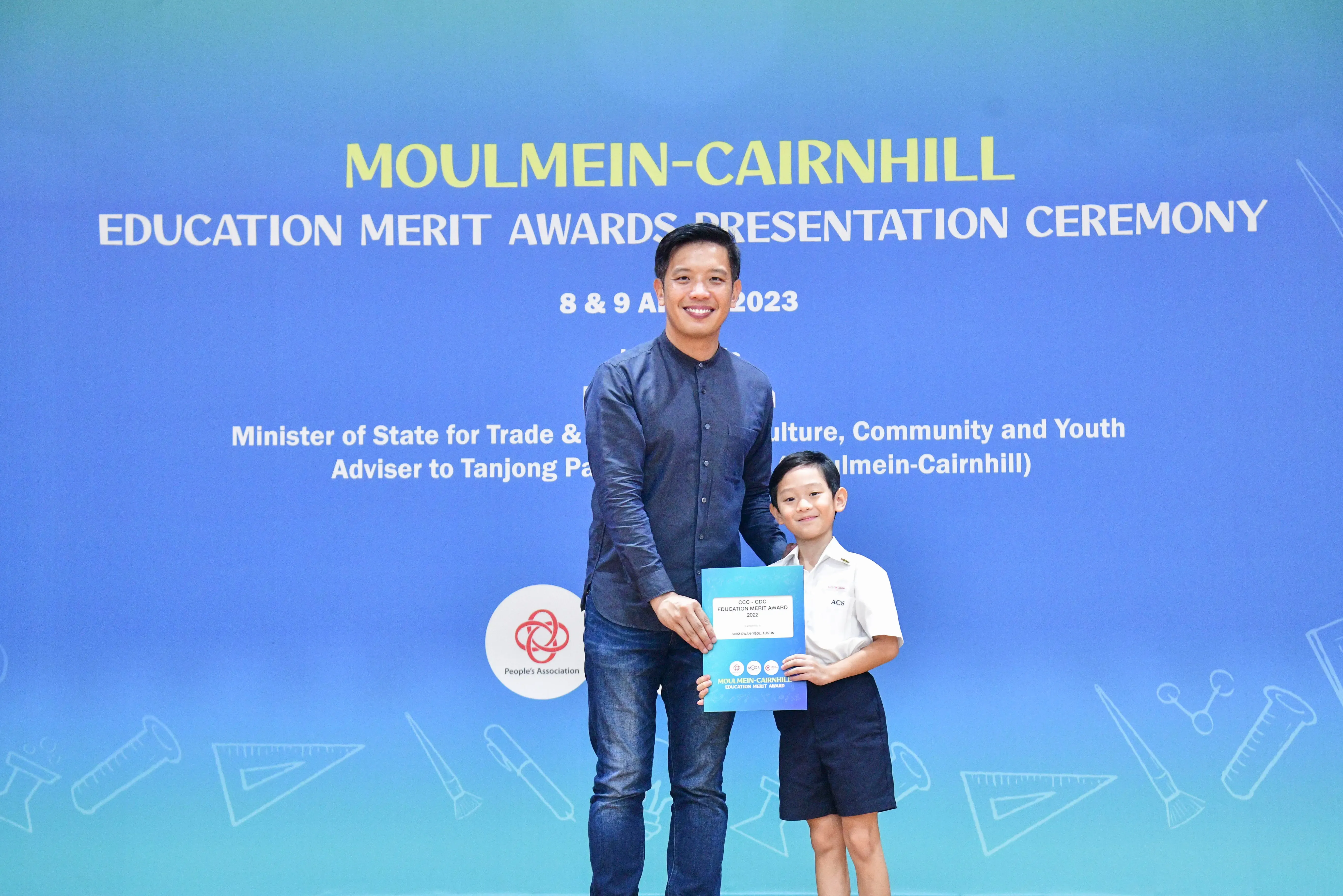 A man and a young boy hold a certificate together at the Moulmein-Cairnhill Education Merit Awards Ceremony 2023.