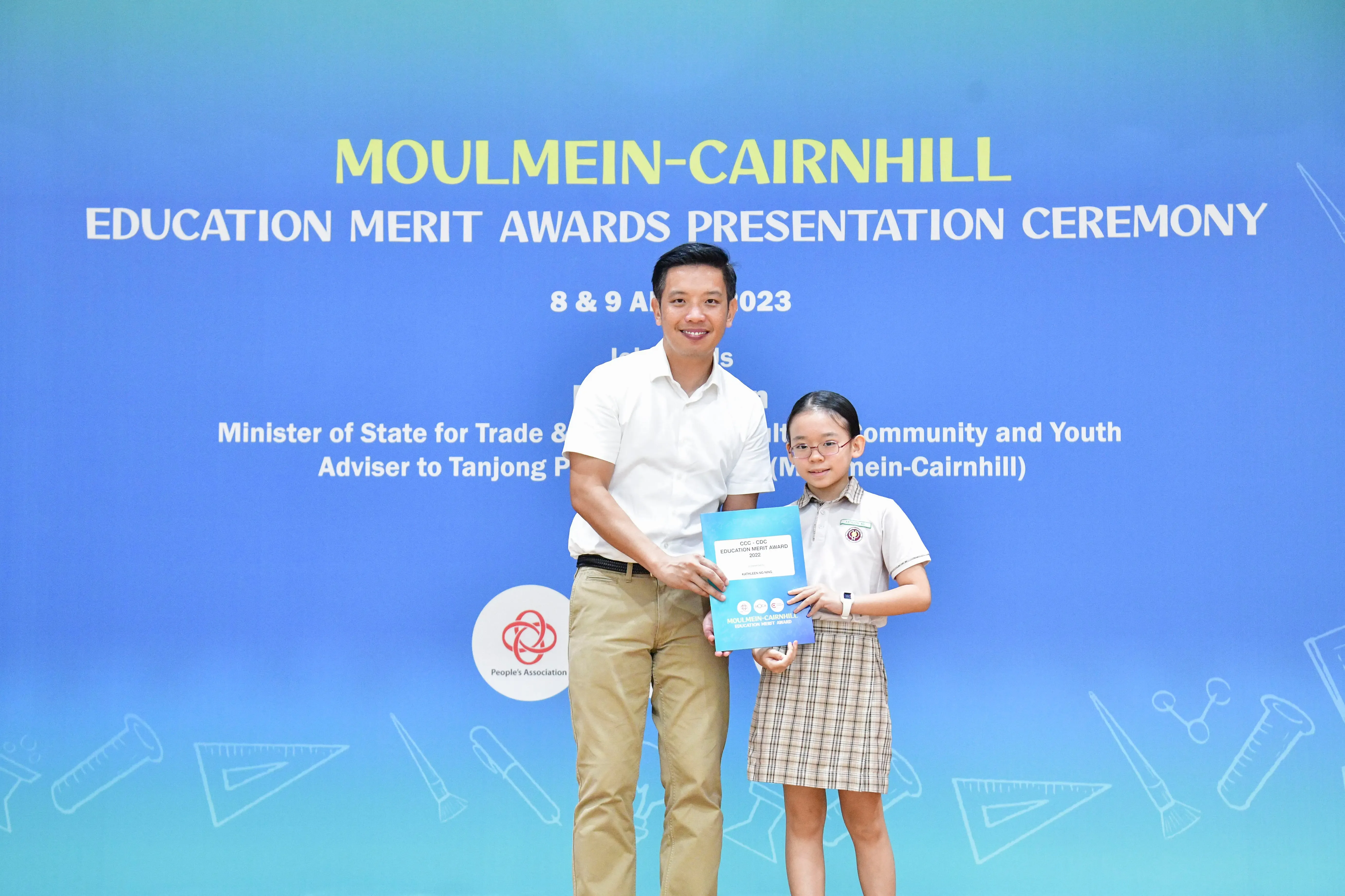A man and a young girl in school uniform hold an award certificate at the Moulmein-Cairnhill Education Merit Awards 2023.