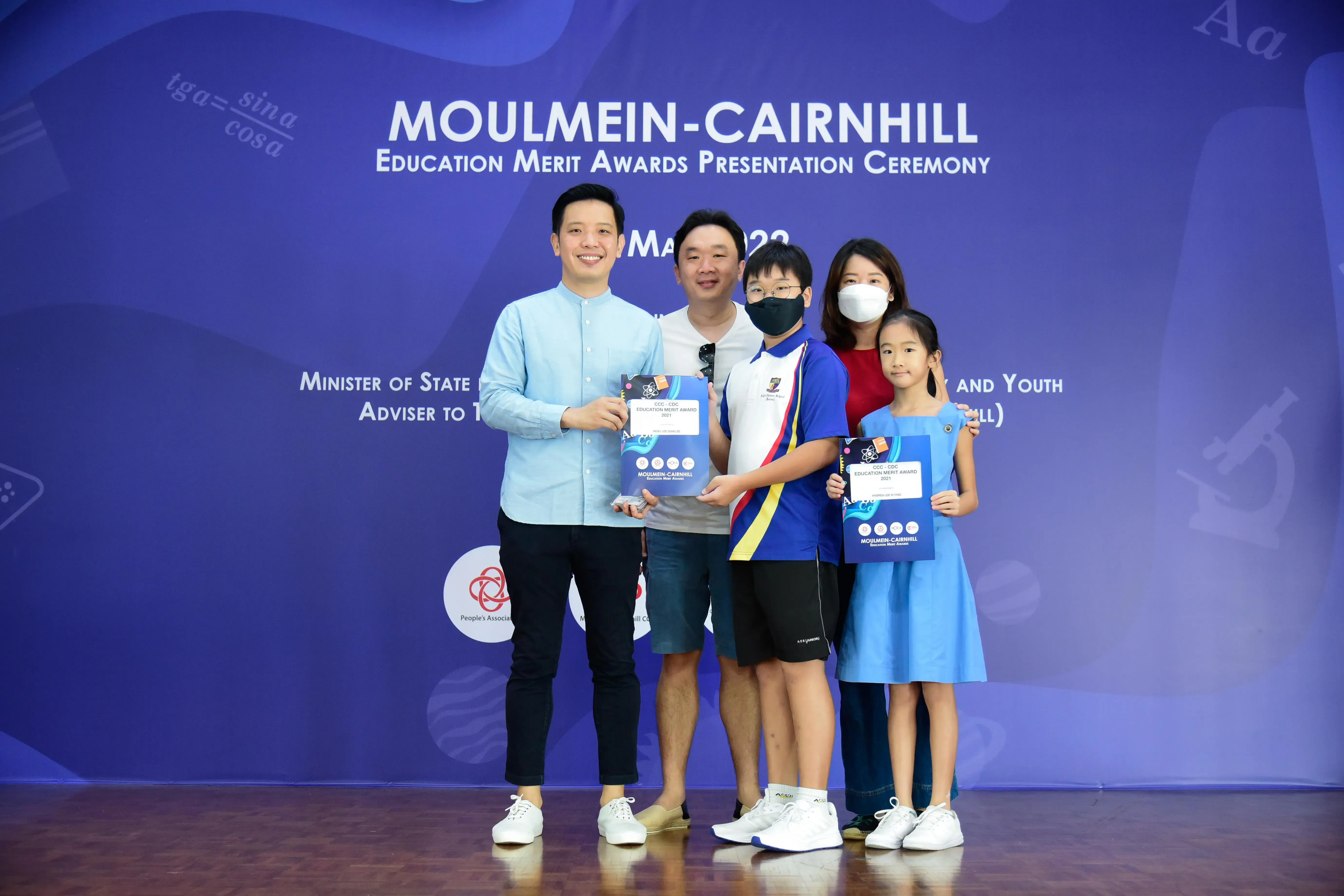 Five people pose holding award certificates at the Moulmein-Cairnhill Education Merit Awards Presentation Ceremony.