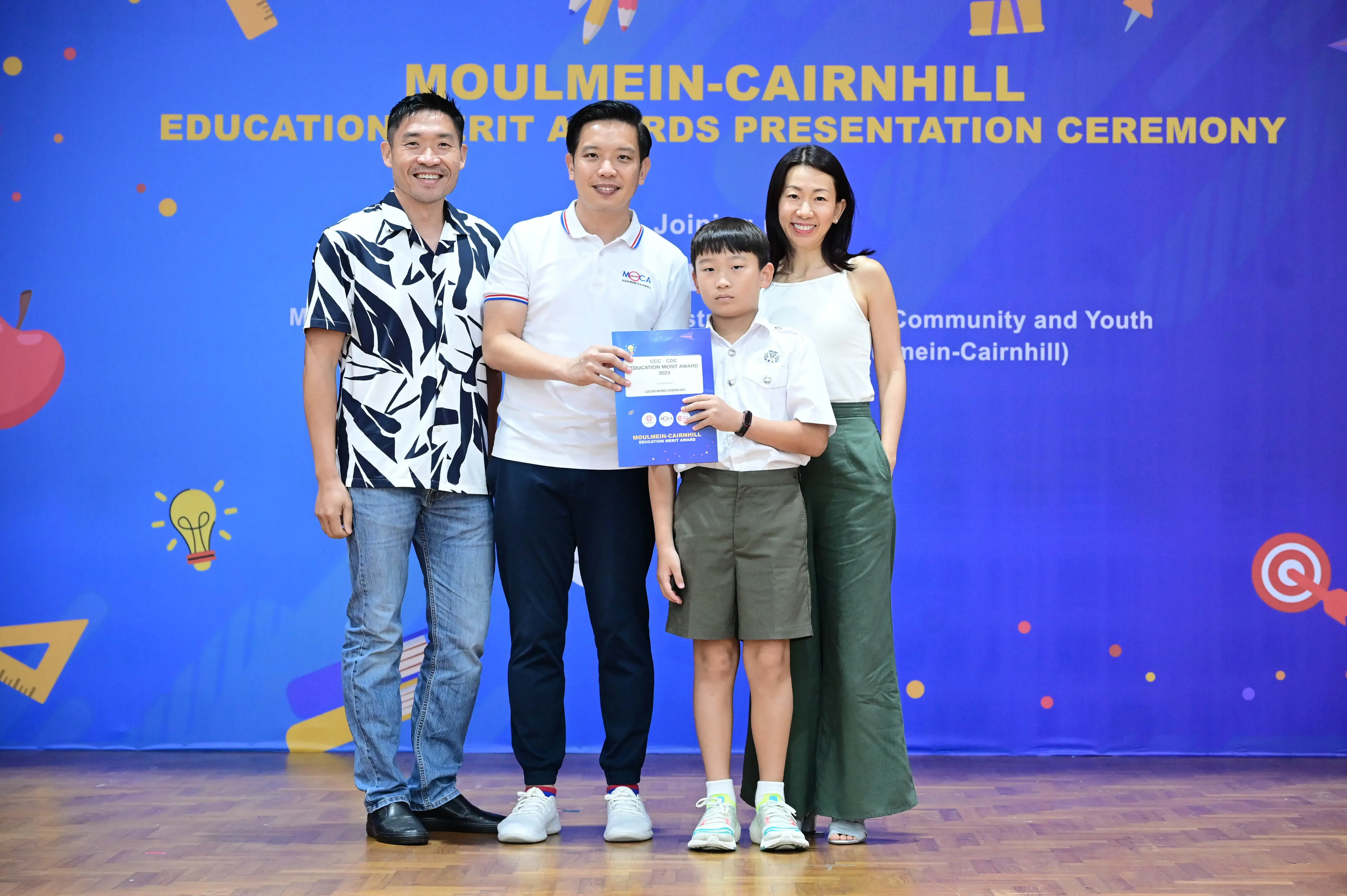 Four people pose with a certificate at the Moulmein-Cairnhill Education Merit Awards Presentation Ceremony.