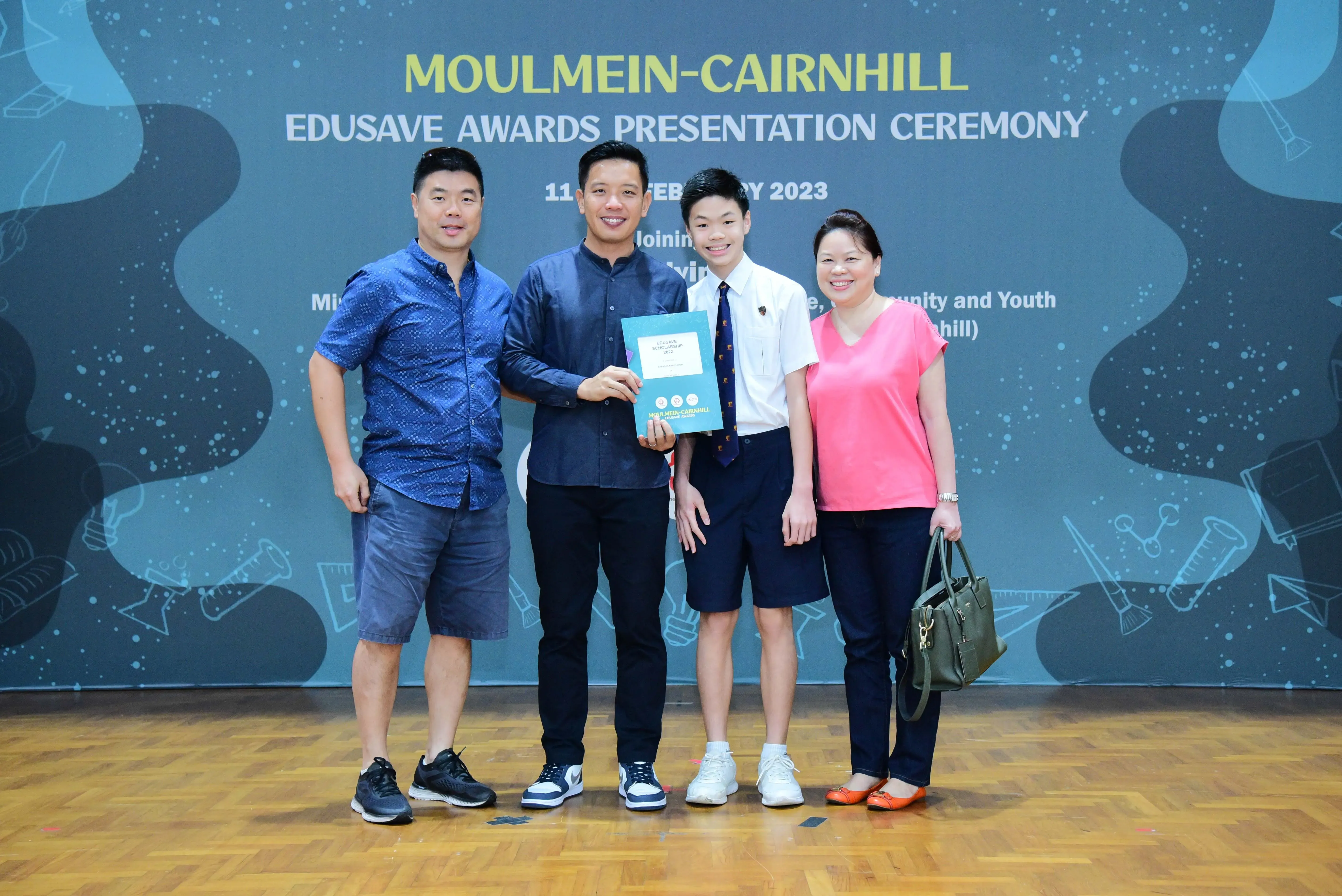 Four people pose at the Moulmein-Cairnhill Edusave Awards Presentation Ceremony 2023, holding a certificate.