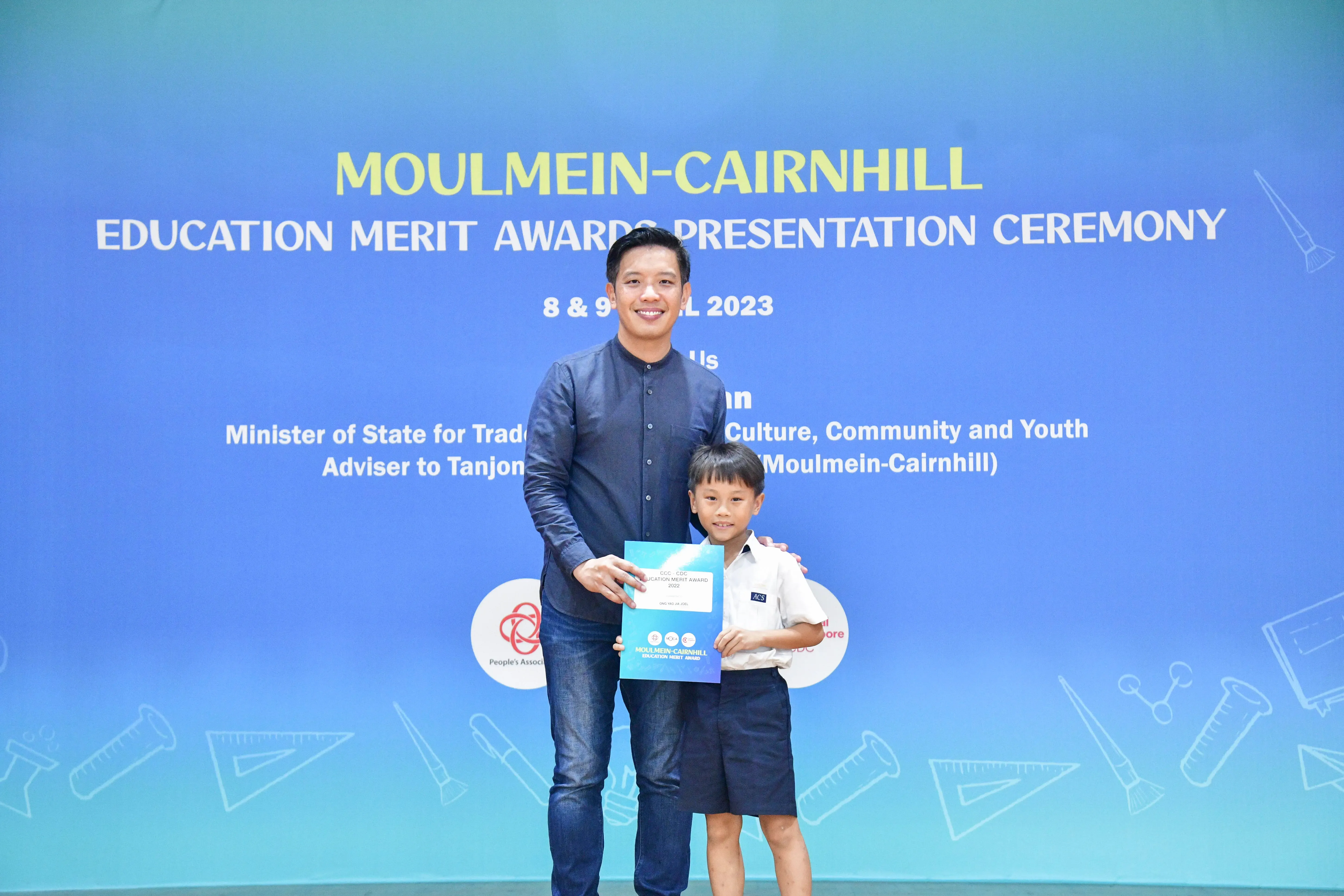 A man and a young boy pose together holding a certificate at the Moulmein-Cairnhill Education Merit Awards 2023.