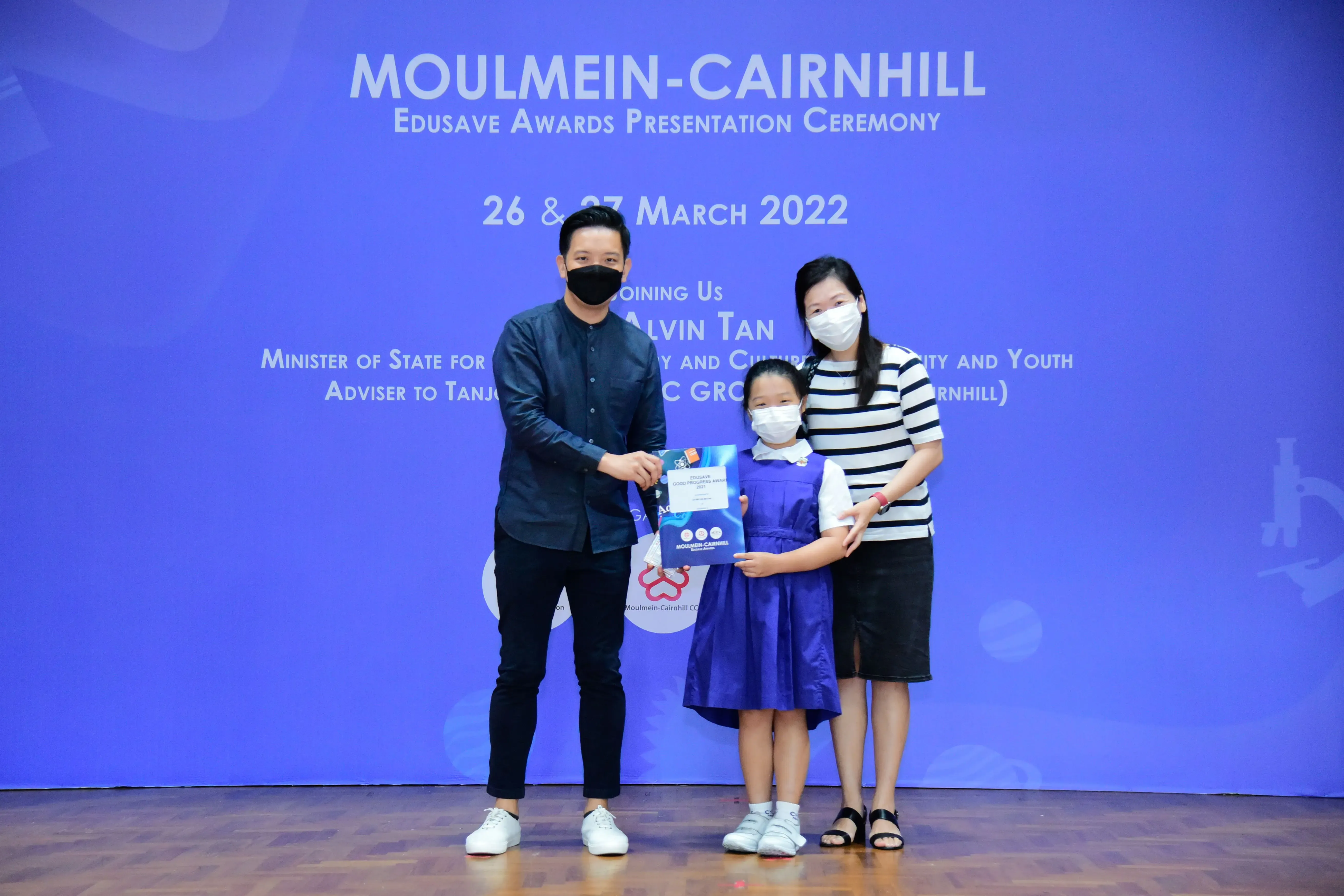 Three masked people pose holding an award at the Moulmein-Cairnhill Edusave Awards Ceremony, March 2022.
