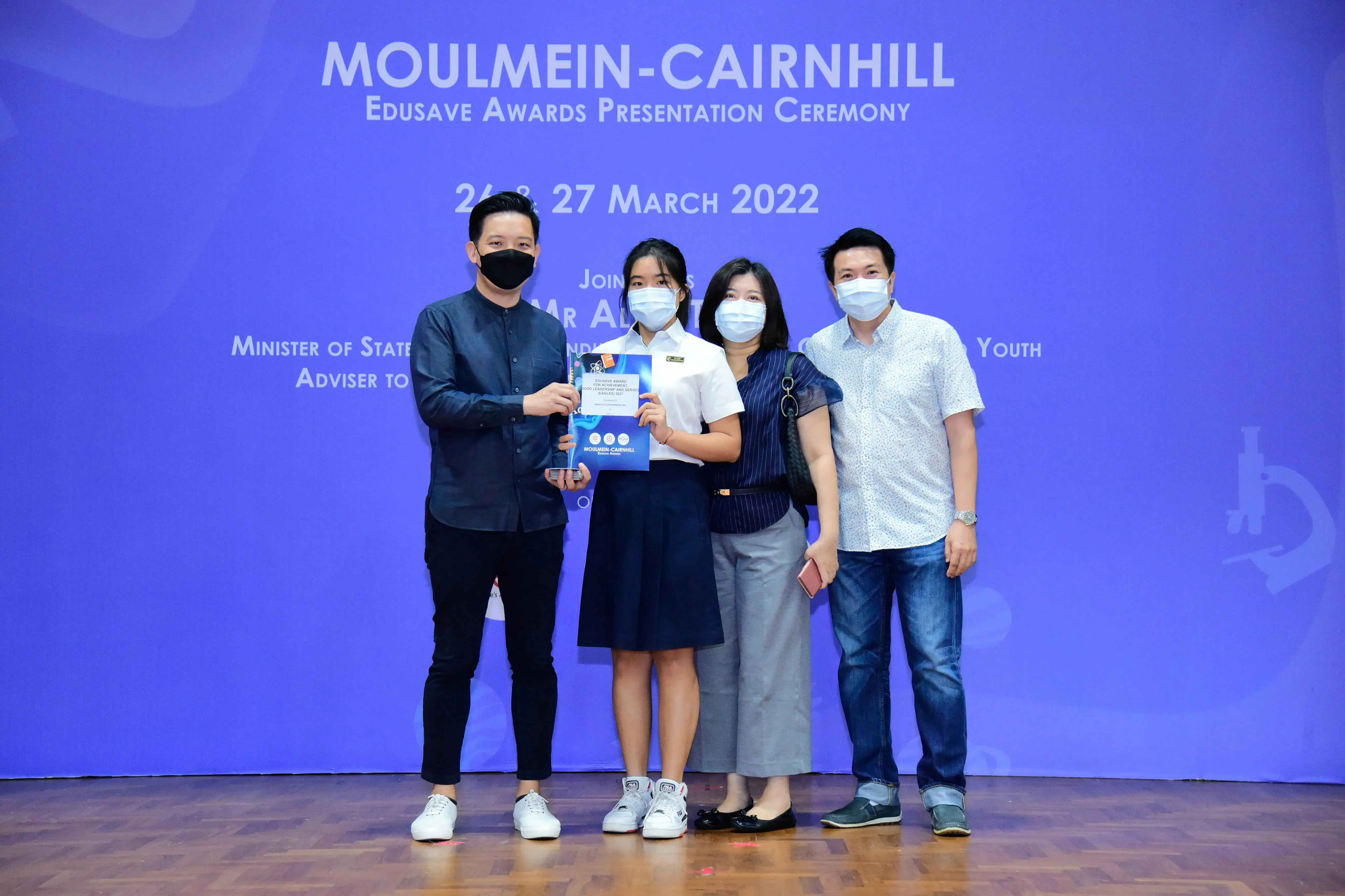 Four masked people pose at the Moulmein-Cairnhill Edusave Awards Presentation Ceremony on 26-27 March 2022.