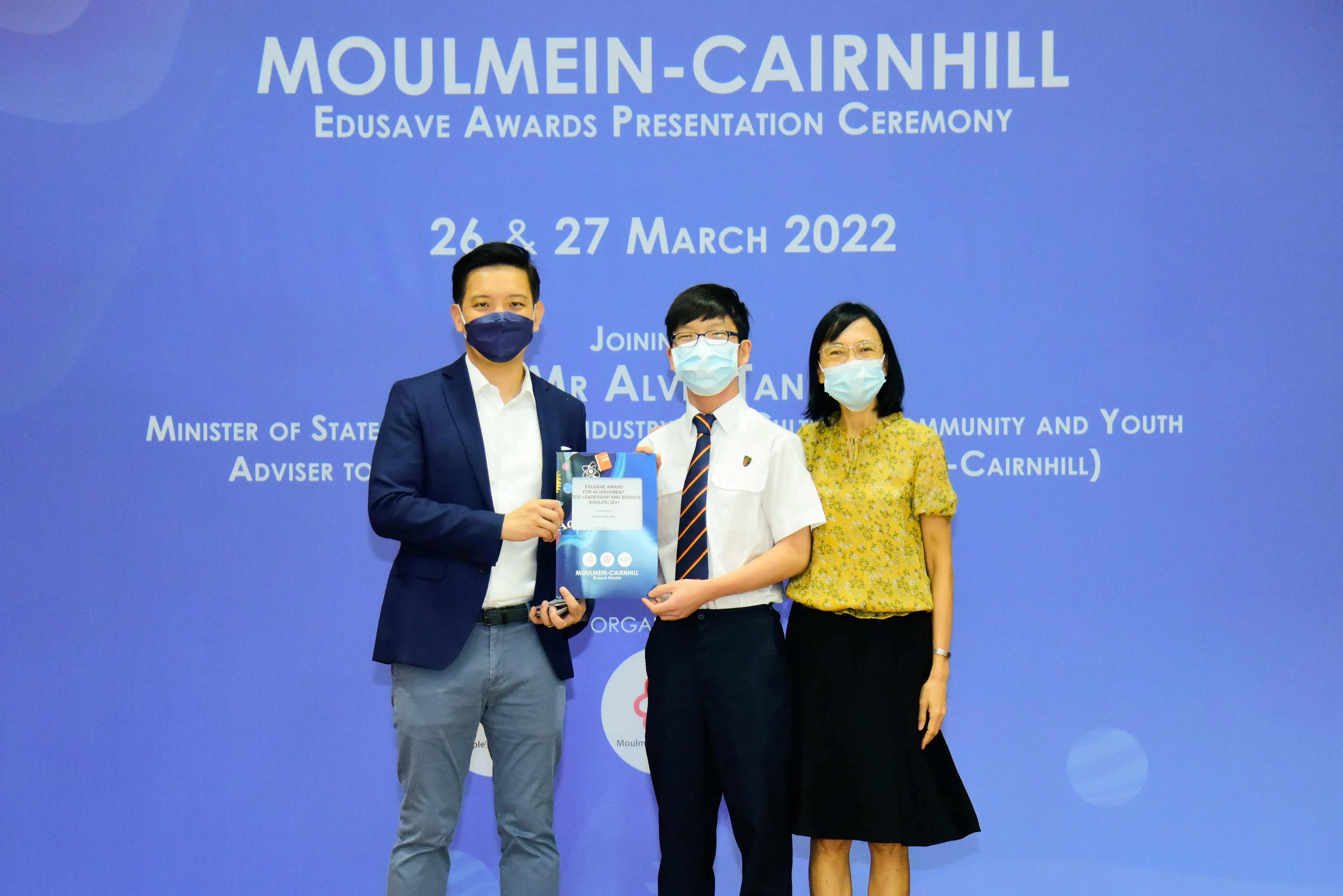 Three masked people pose at the Moulmein-Cairnhill Edusave Awards Presentation Ceremony on 26-27 March 2022.