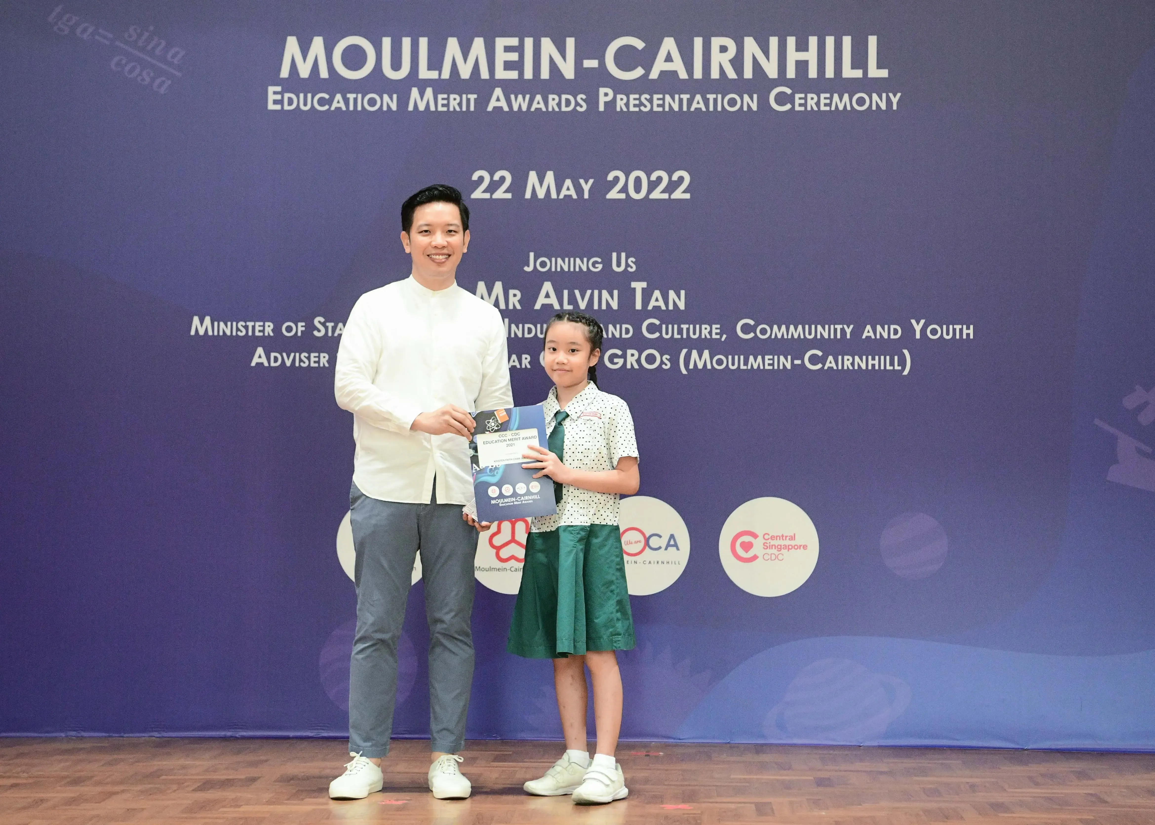 Man and young girl hold an award certificate at Moulmein-Cairnhill Education Merit Awards Ceremony, 22 May 2022.