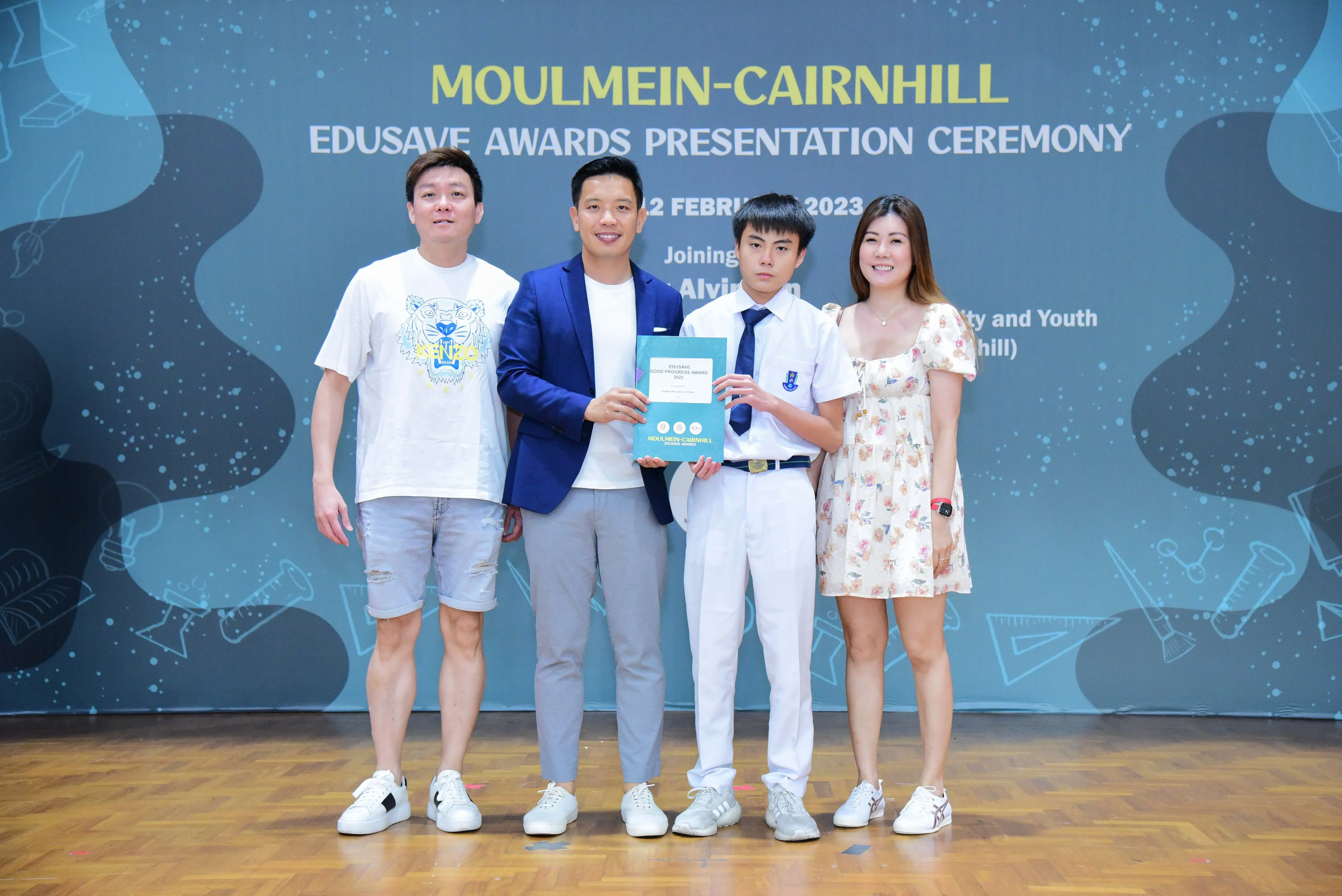 Four people pose holding a certificate at the Moulmein-Cairnhill Edusave Awards Presentation Ceremony, February 2023.
