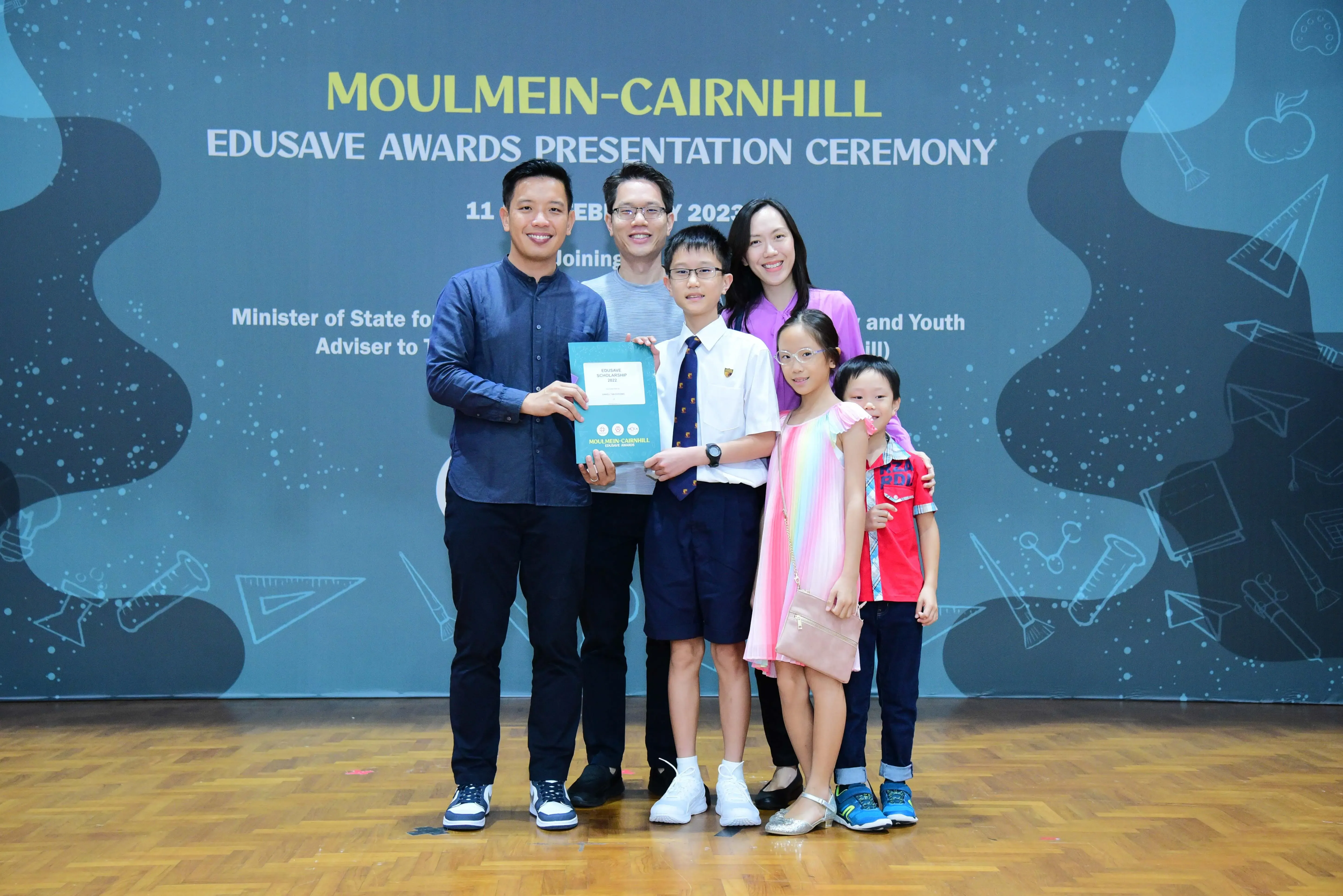 Group of adults and children posing with an award at the Moulmein-Cairnhill Edusave Awards Presentation Ceremony 2023.