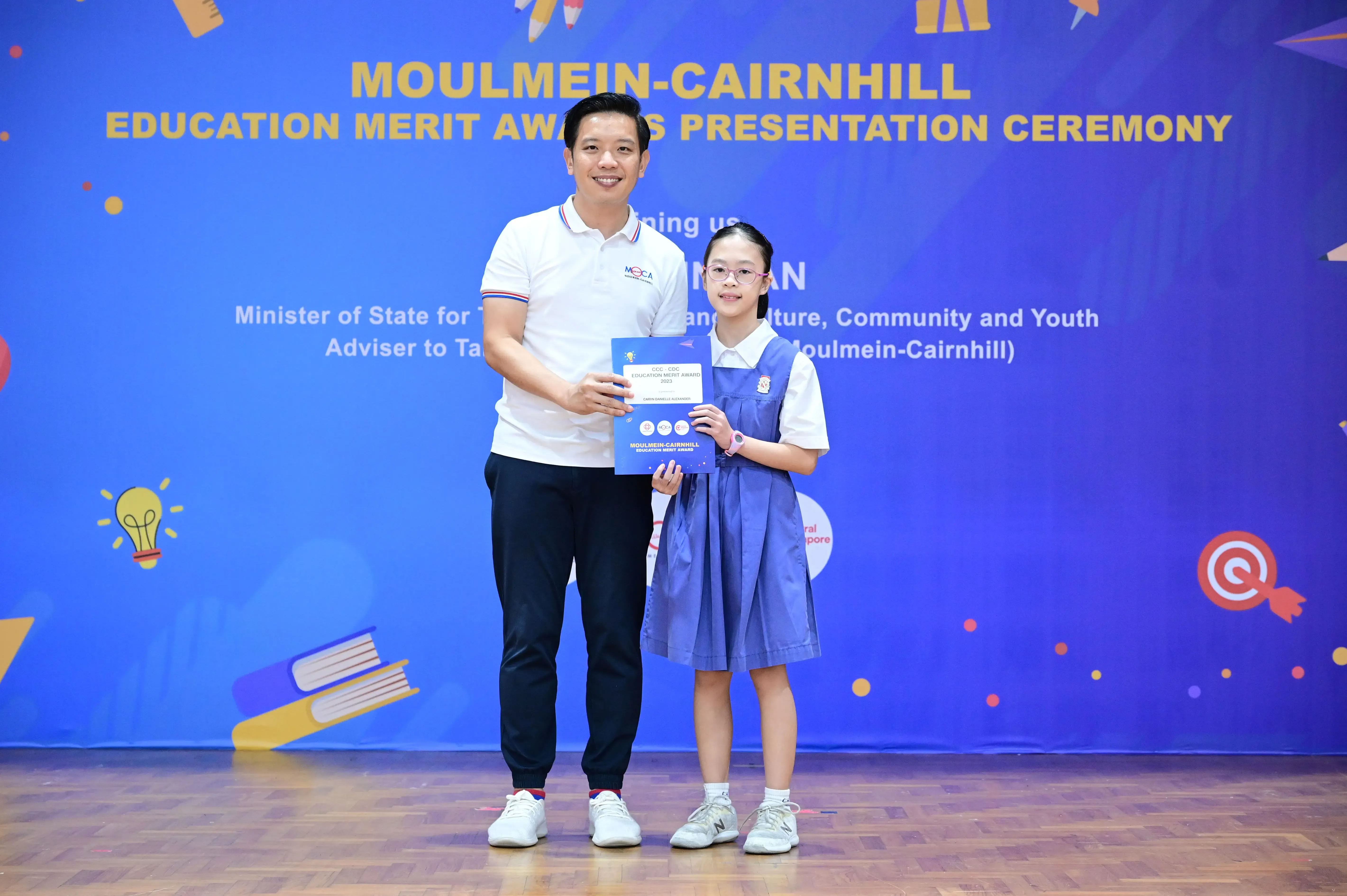 Man and young girl holding an award certificate at the Moulmein-Cairnhill Education Merit Awards Presentation Ceremony.