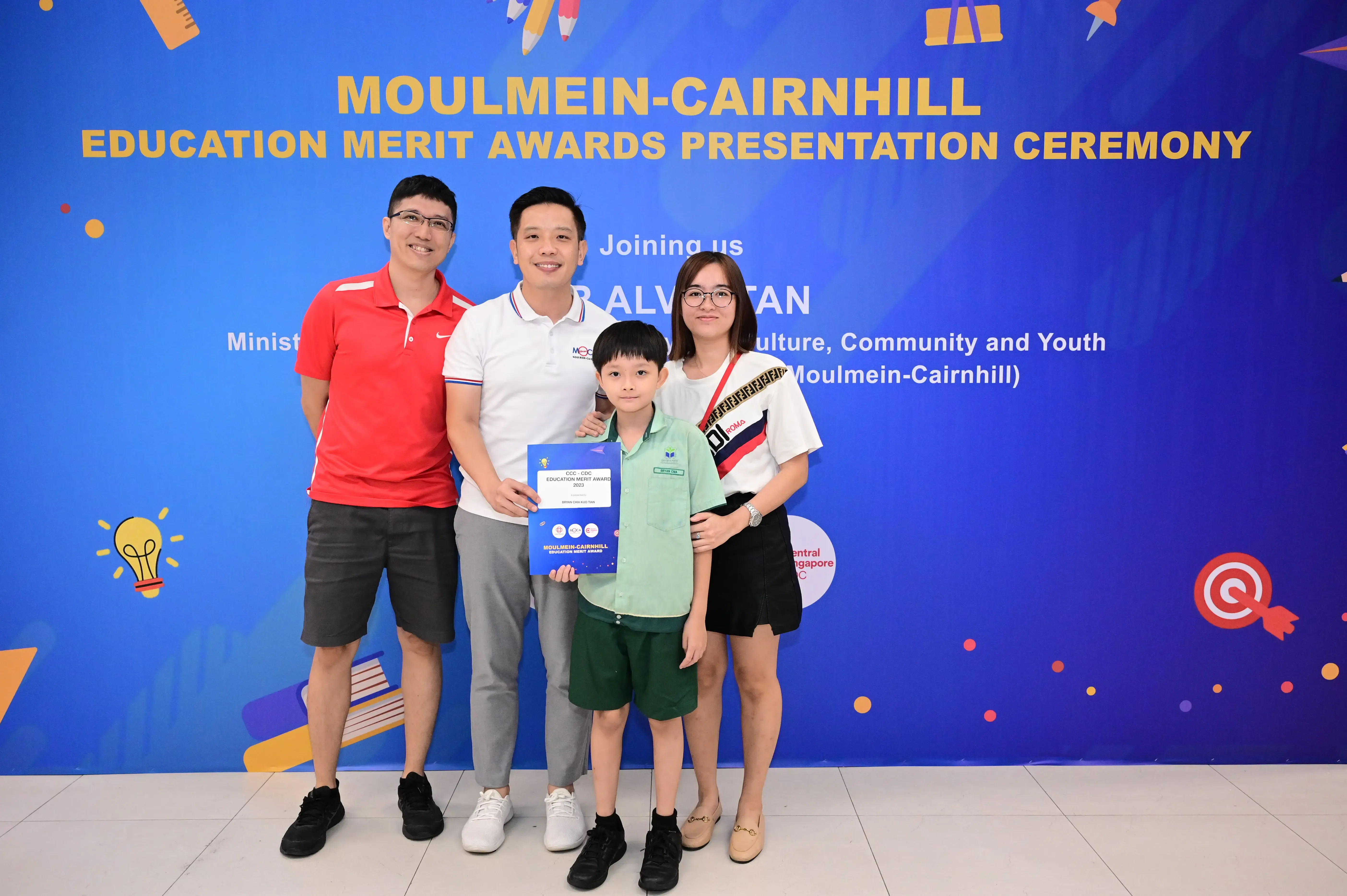 Three adults and a boy holding a certificate pose at the Moulmein-Cairnhill Education Merit Awards ceremony.