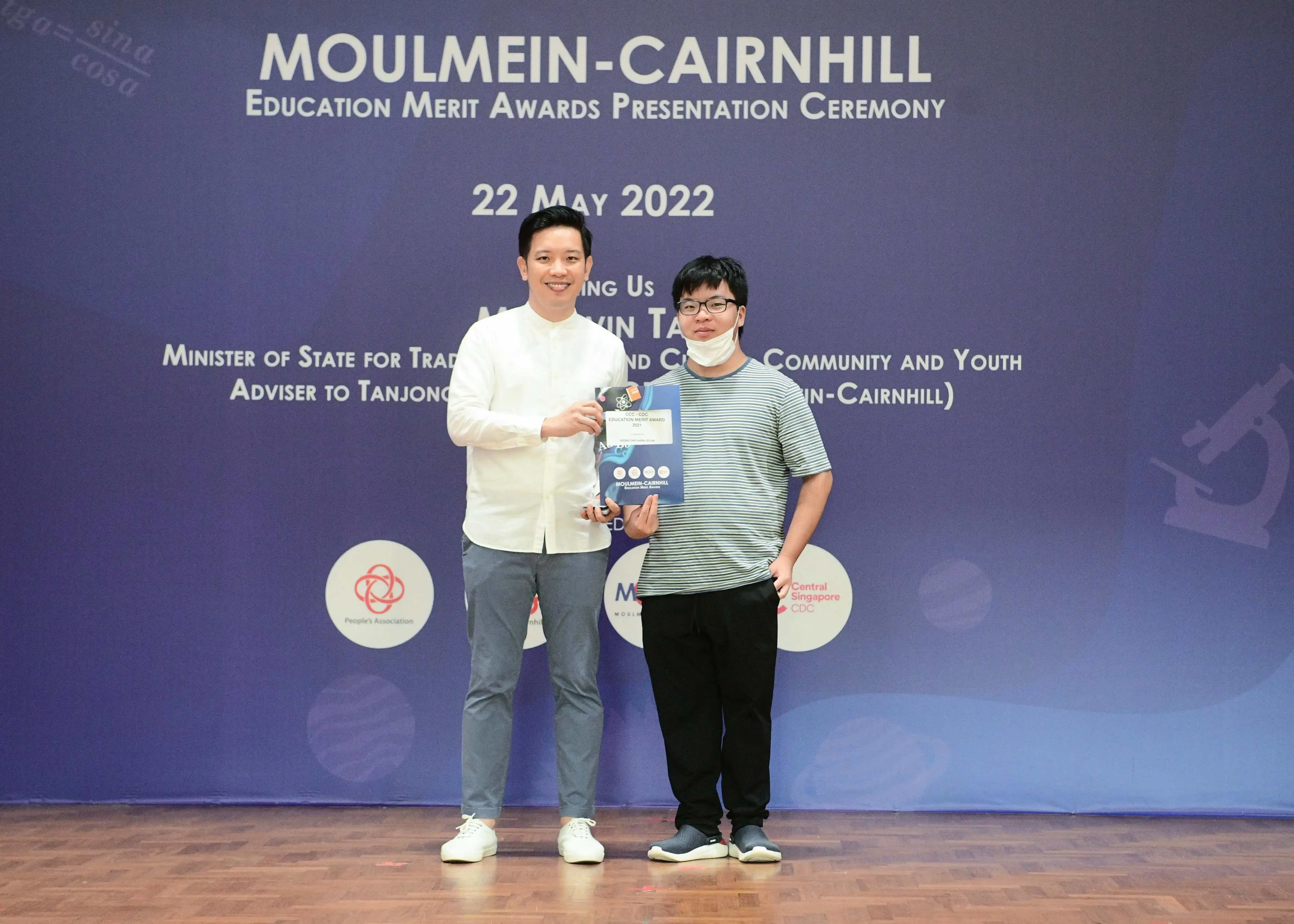 Two people pose holding an award booklet at the Moulmein-Cairnhill Education Merit Awards Ceremony on 22 May 2022.
