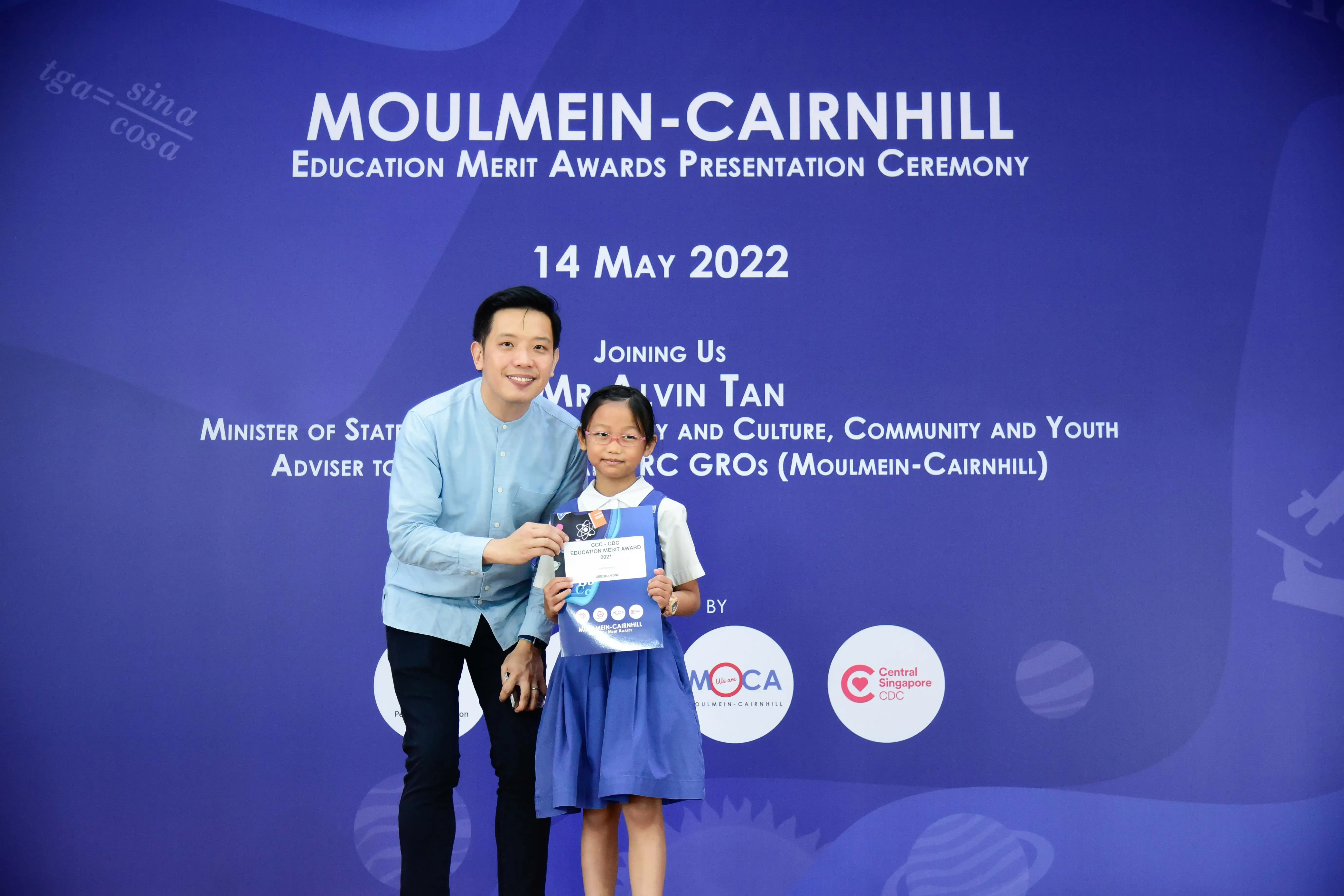 A man and a young girl hold an award certificate at the Moulmein-Cairnhill Education Merit Awards on 14 May 2022.