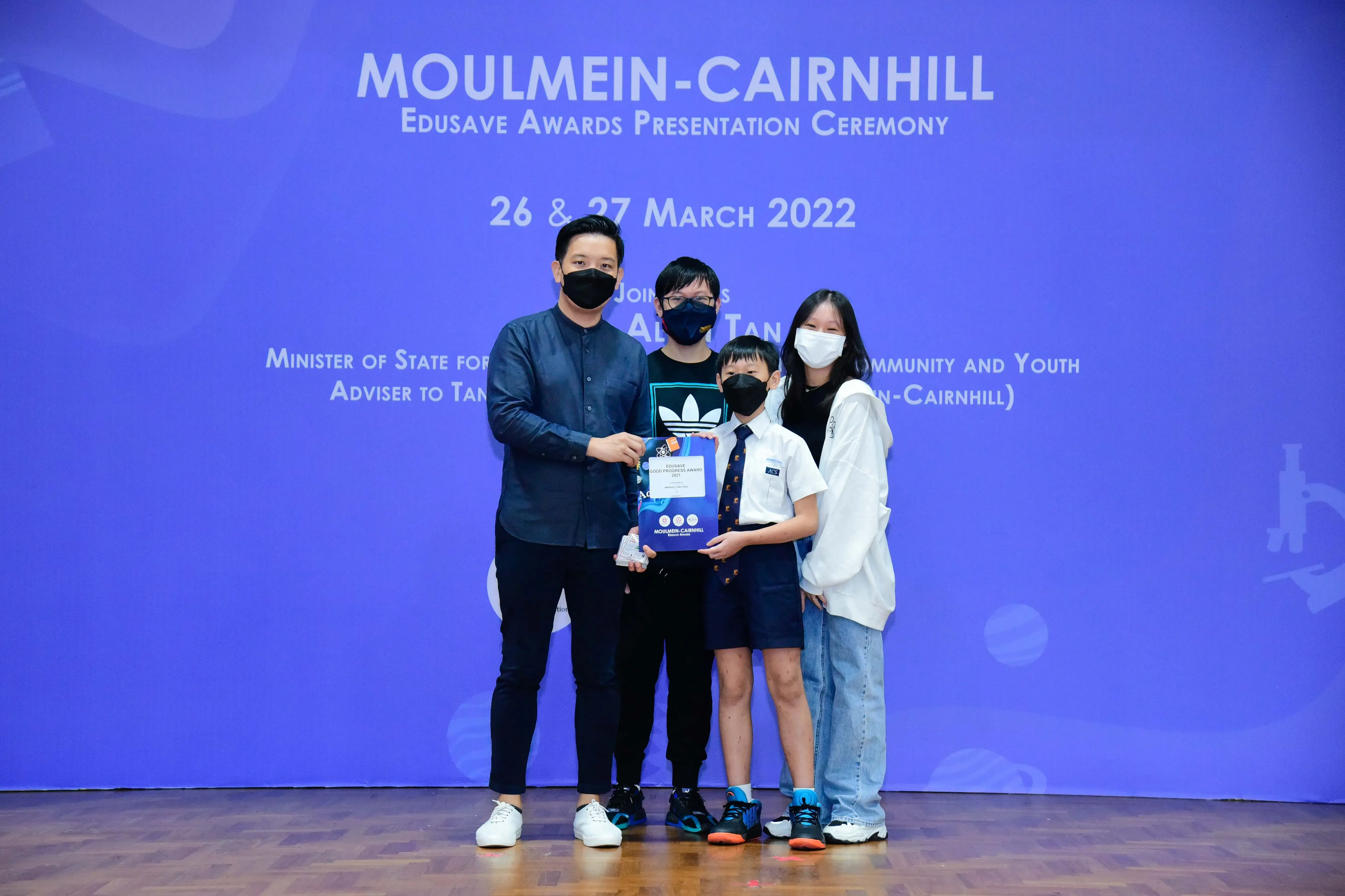 Four masked people pose with an award at the Moulmein-Cairnhill Edusave Awards Ceremony, March 2022.