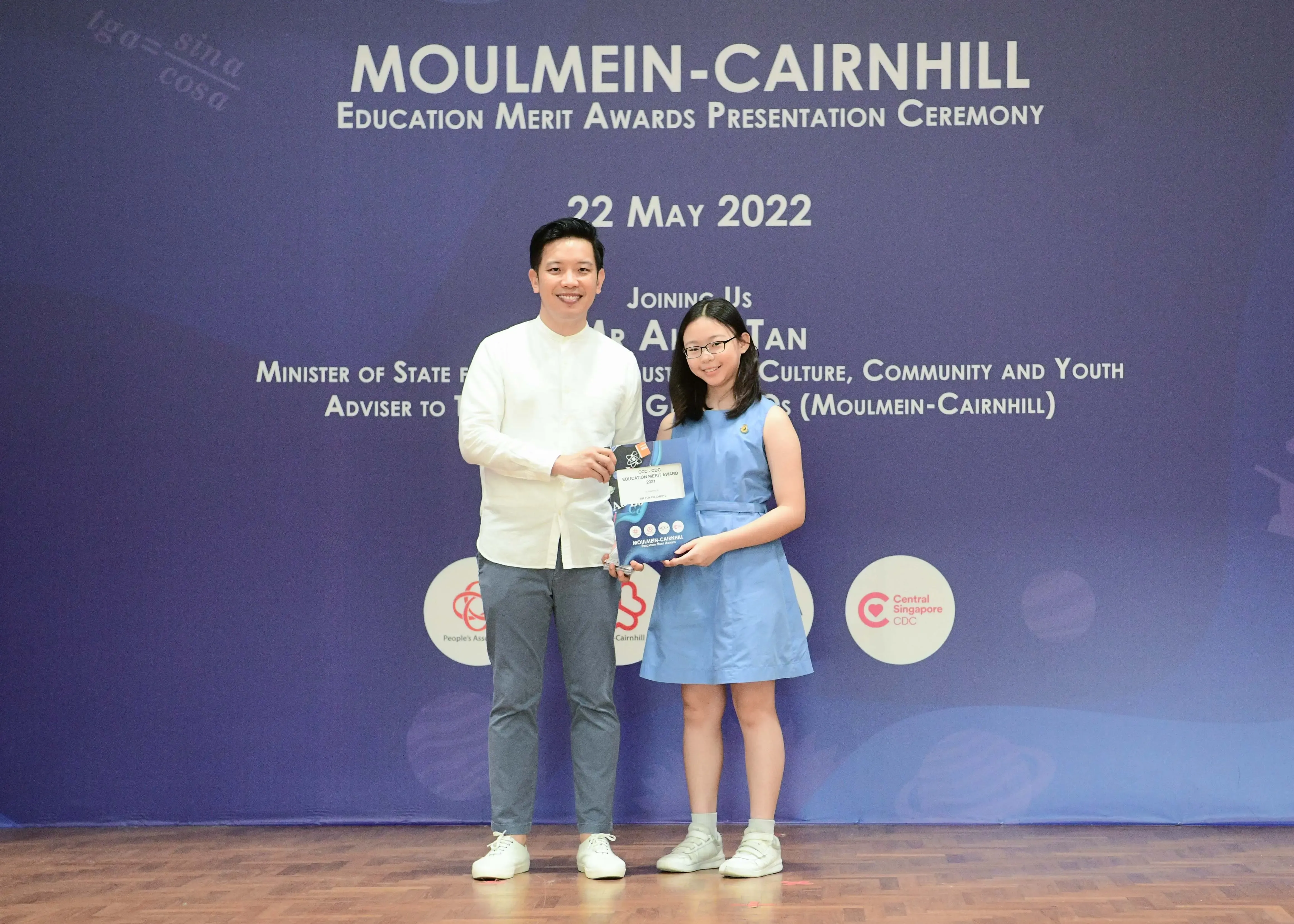 A man and a young girl pose together holding an award at the Moulmein-Cairnhill Education Merit Awards Ceremony on 22 May 2022.