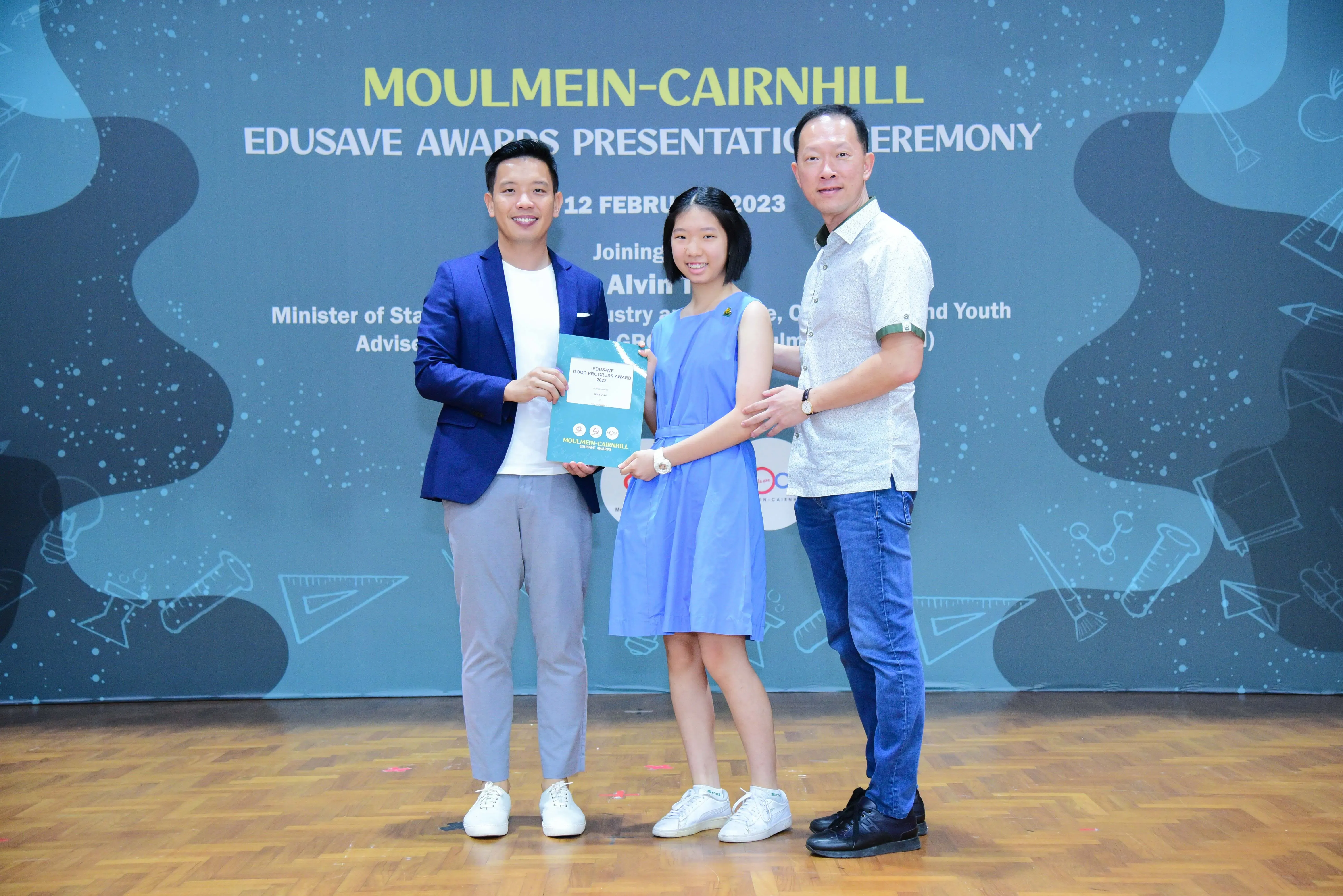 Three people pose on stage at the Moulmein-Cairnhill Edusave Awards Presentation Ceremony on 12 February 2023.