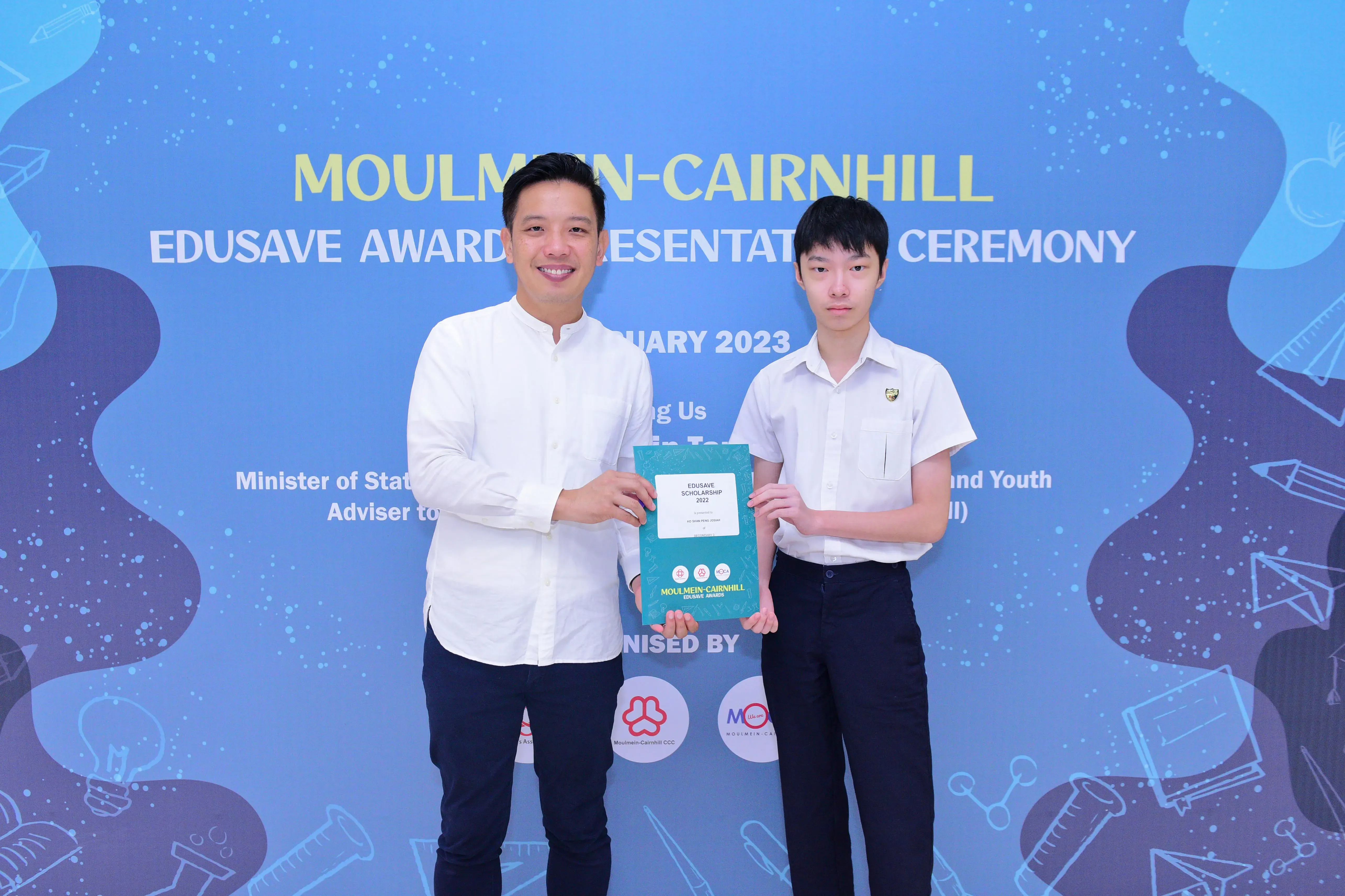 Two people hold an Edusave Scholarship certificate at the Moulmein-Cairnhill Awards Presentation Ceremony 2023.