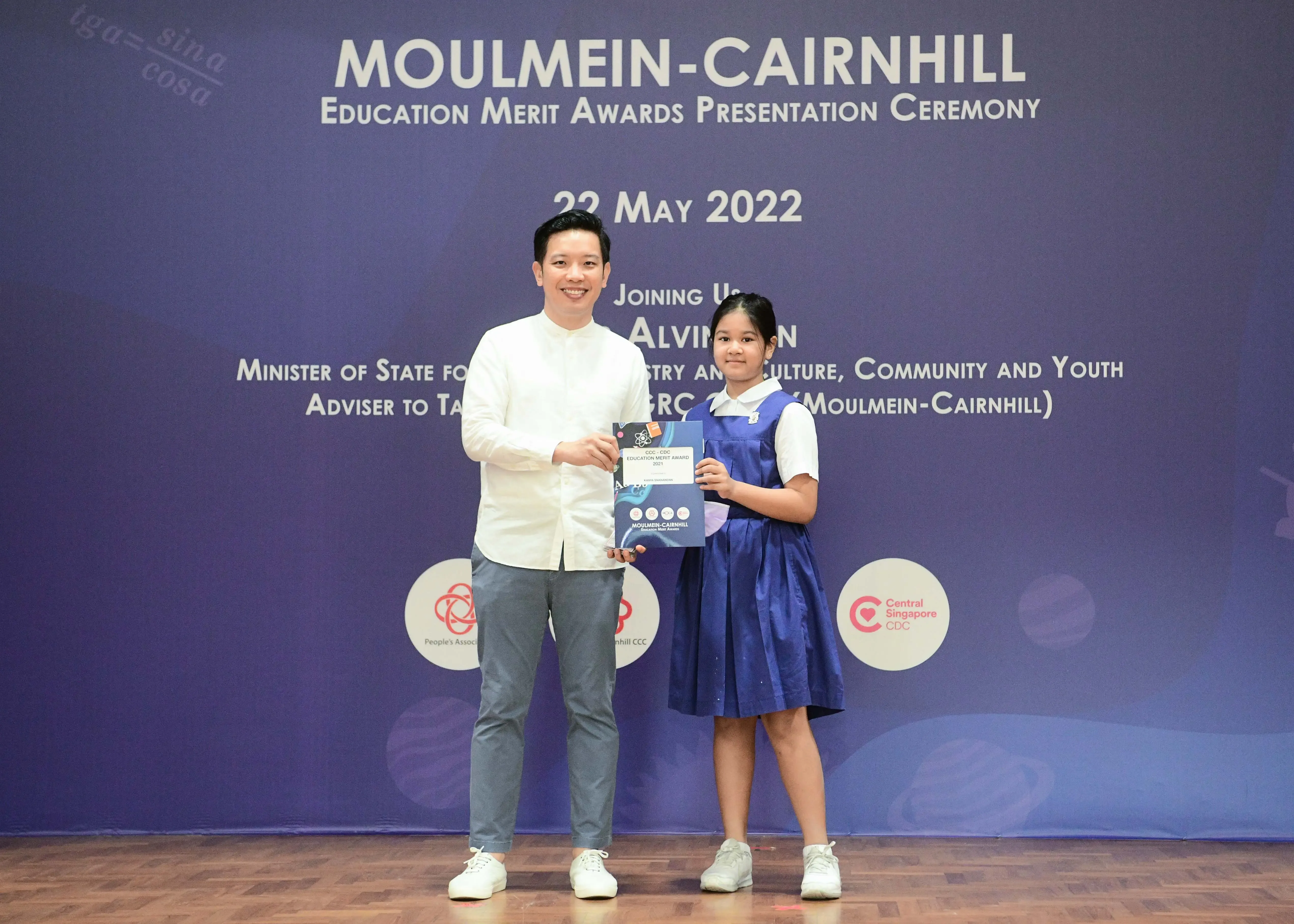 A man and a young girl hold an award certificate at the Moulmein-Cairnhill Education Merit Awards Ceremony, 22 May 2022.