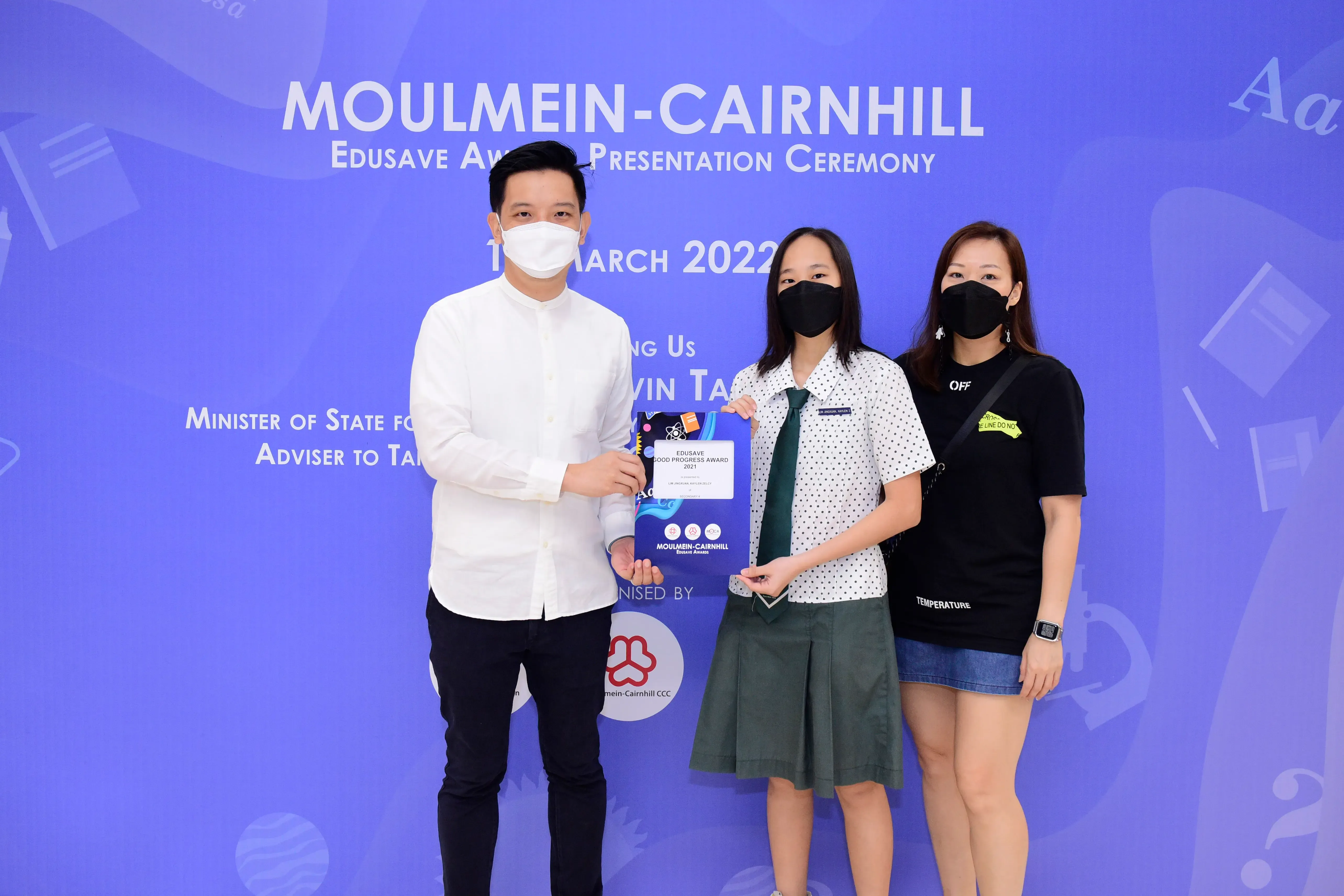 Three masked people pose at the Moulmein-Cairnhill Edusave Award Presentation Ceremony, March 2022.