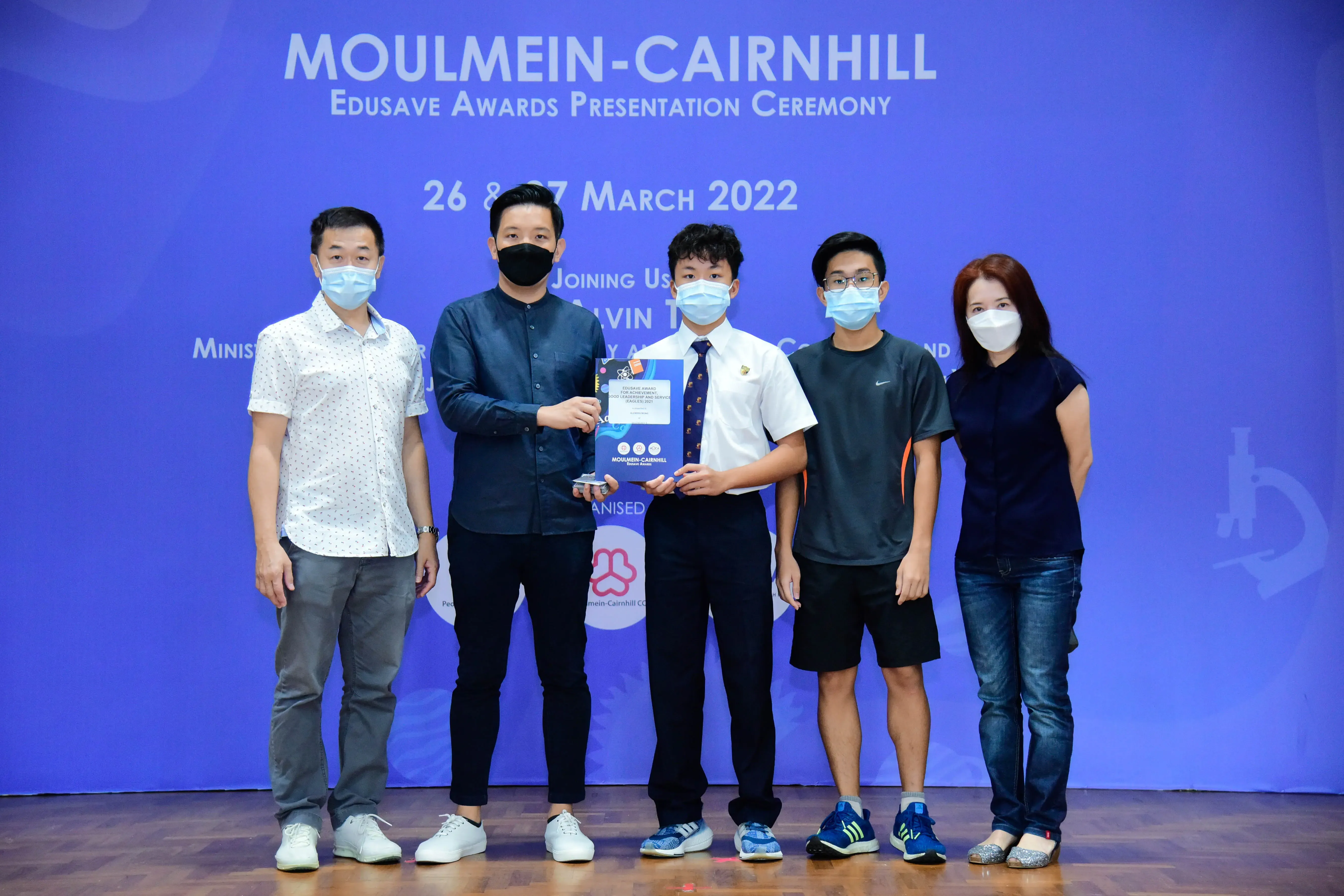 Five masked people pose at the Moulmein-Cairnhill Edusave Awards Presentation Ceremony on 26-27 March 2022.