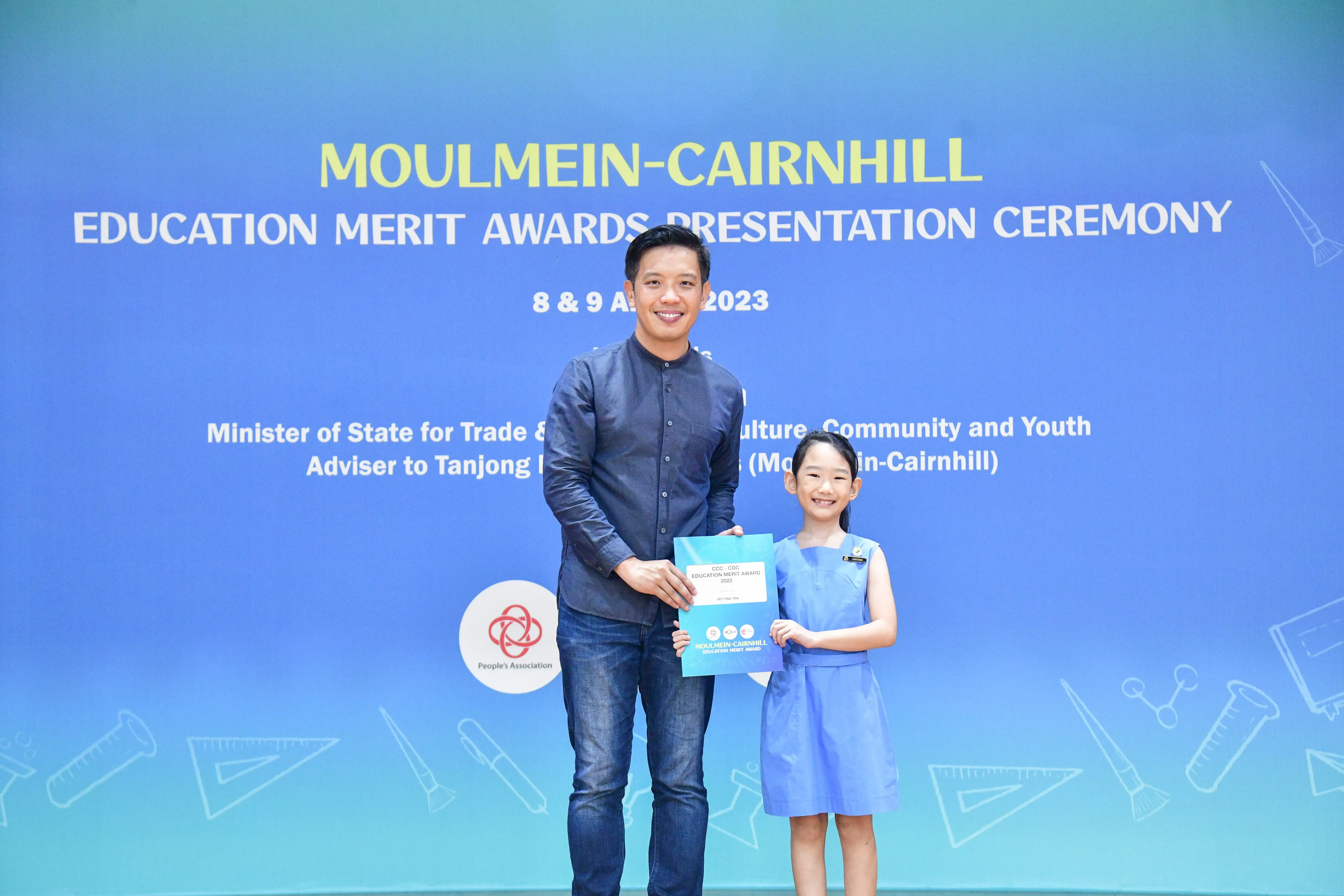 A man and a young girl hold a certificate at the Moulmein-Cairnhill Education Merit Awards Ceremony 2023.