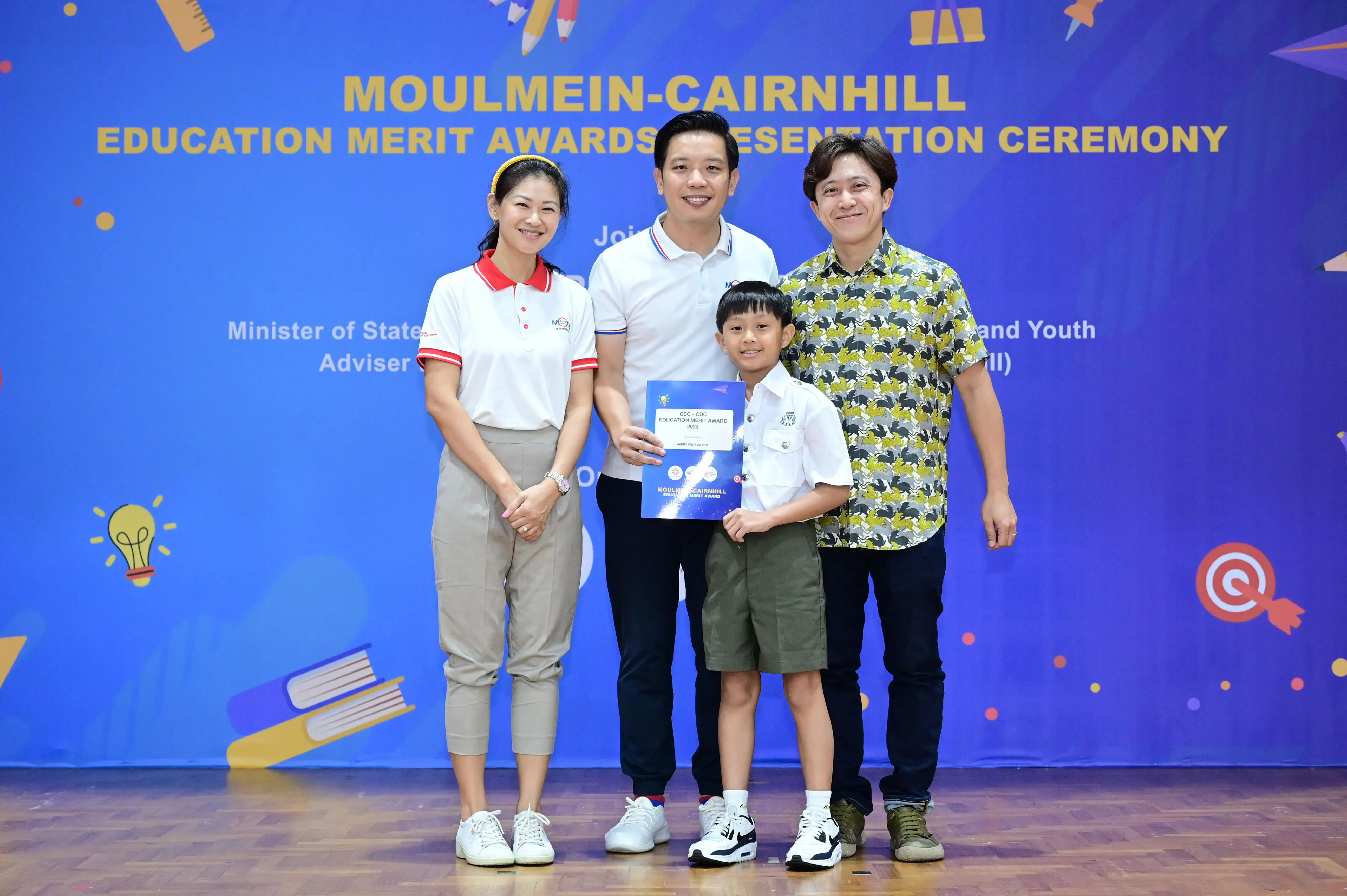 Three adults and a boy holding an award certificate pose at the Moulmein-Cairnhill Education Merit Awards Ceremony.