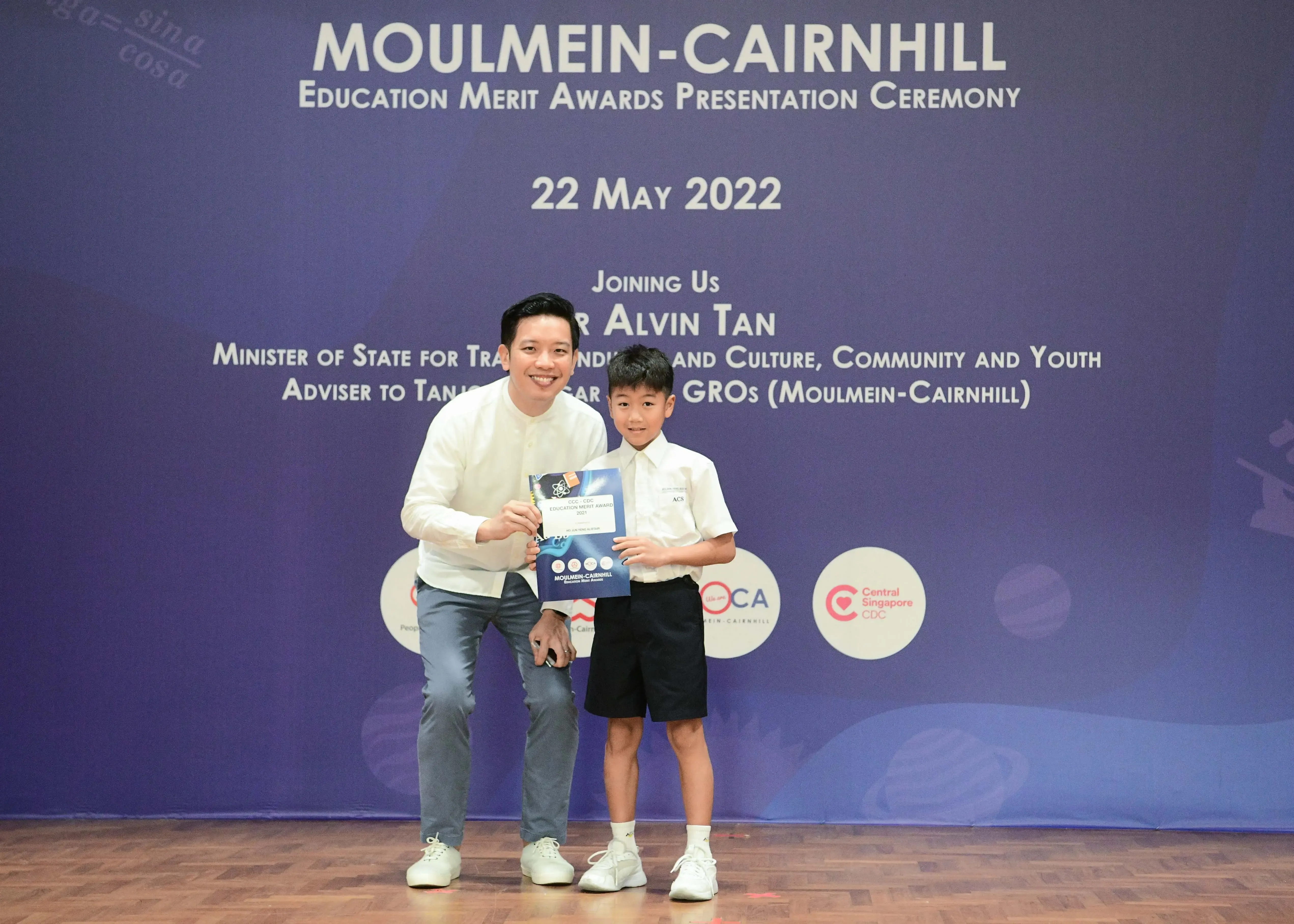 A man and a young boy hold a certificate at the Moulmein-Cairnhill Education Merit Awards on 22 May 2022.